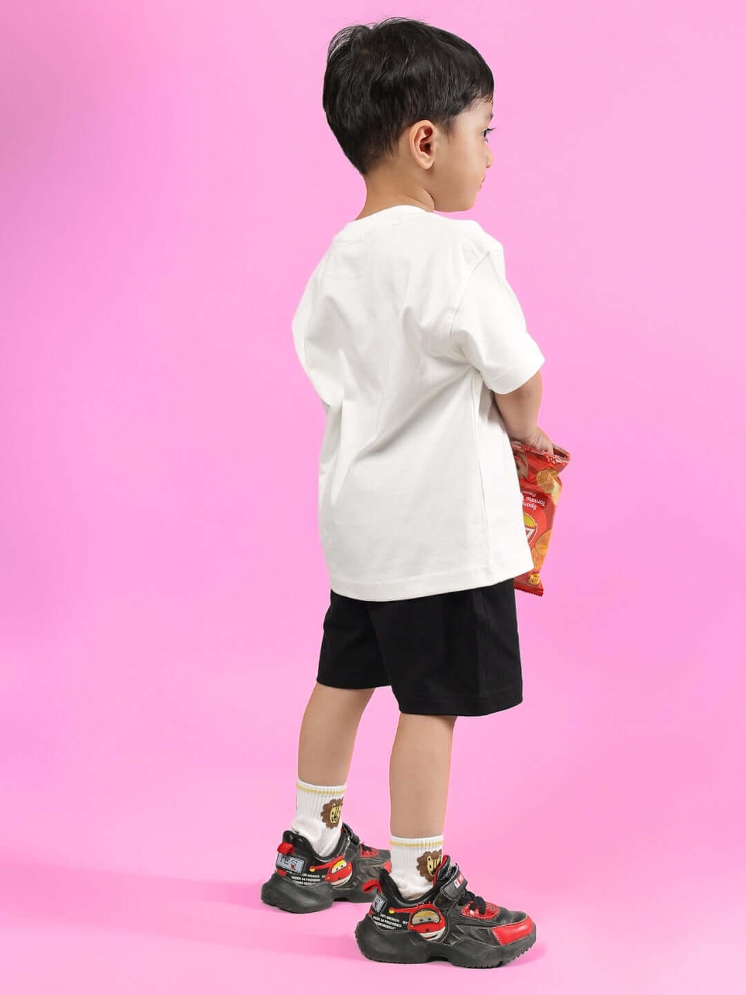 Child wearing BRUNO CO-ORD FOR BOYS & GIRLS OFF WHITE-BLACK, standing against pink background.