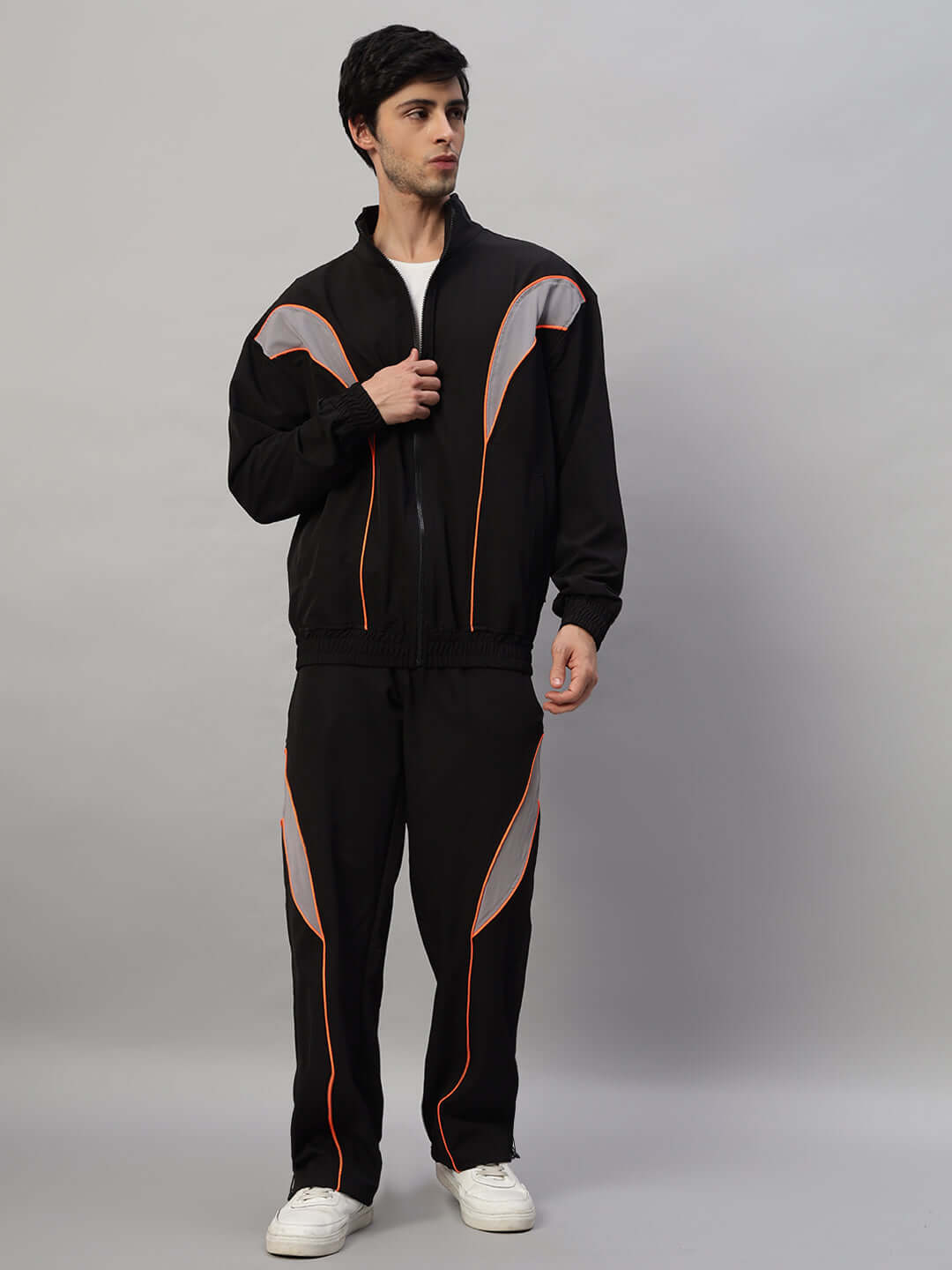 Man wearing black BULLET OVERSIZED CO-ORD SET with orange accents, featuring relaxed fit joggers and elastic waistband, polyester fabric.