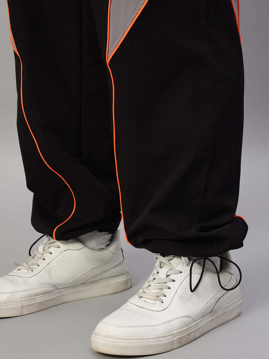 Close-up of BULLET OVERSIZED CO-ORD SET BLACK pants with white sneakers, highlighting bold design and relaxed fit.