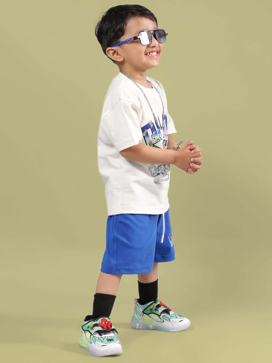 Child wearing BUMBLE CO-ORD FOR BOYS & GIRLS OFF WHITE-R BLUE, smiling and wearing sunglasses, with stylish sneakers on a plain background.