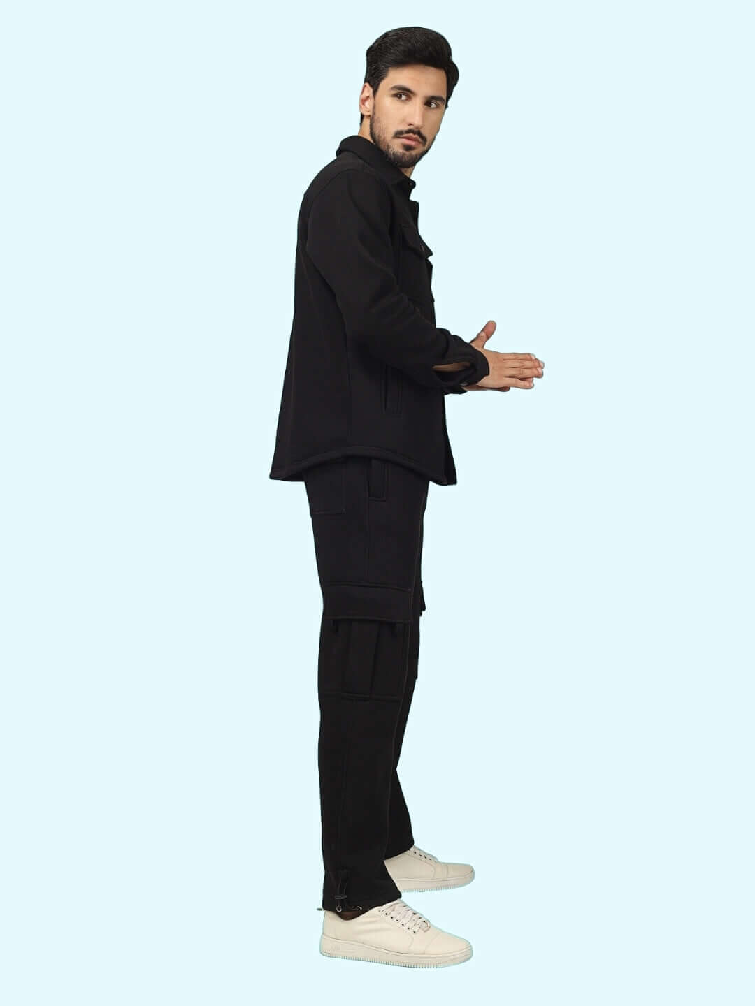 Man wearing Burly Black Overshirt-Cargo Pant Co-Ord Set with white sneakers, side view on a light blue background.