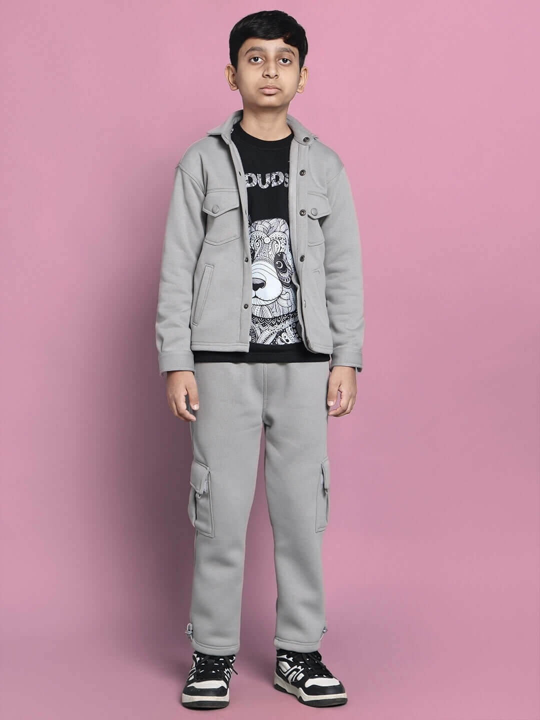 Child wearing a grey Burly fleece pant and jacket set for boys and girls with pockets, standing against a pink background.