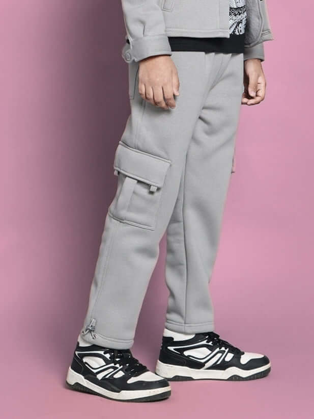 Burly fleece pant for boys and girls in grey, featuring cargo pockets, modeled on a child against a pink background.