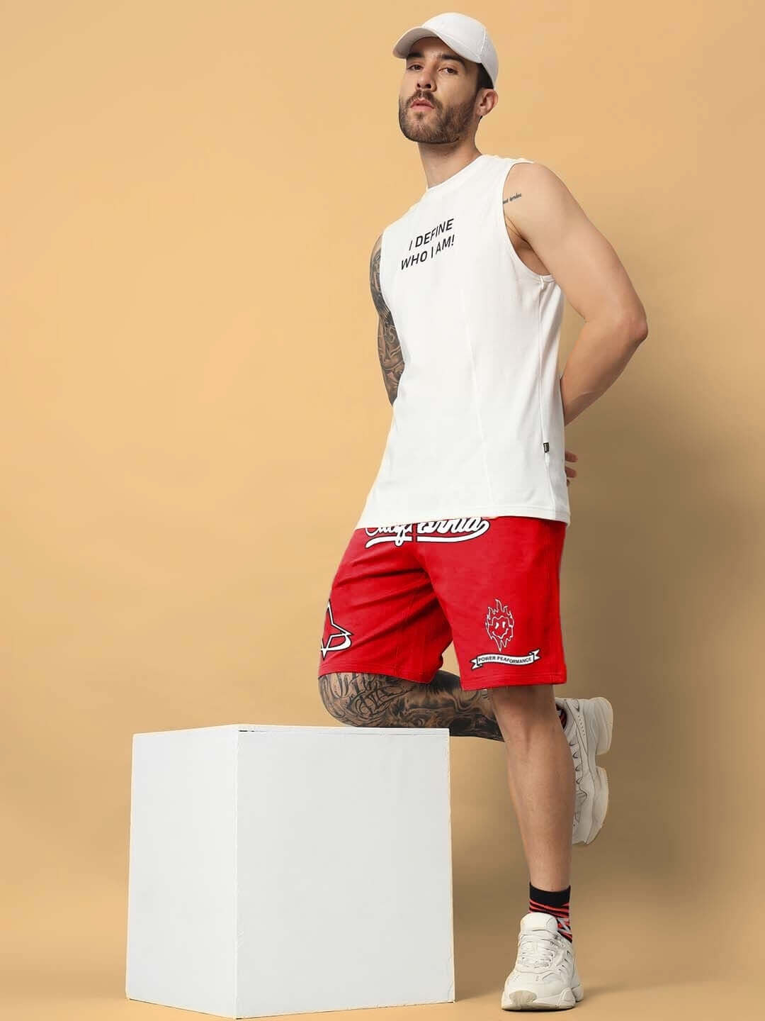Model wearing California Regular Fit Red Shorts with a casual white tank top and cap, showcasing summer fashion style.