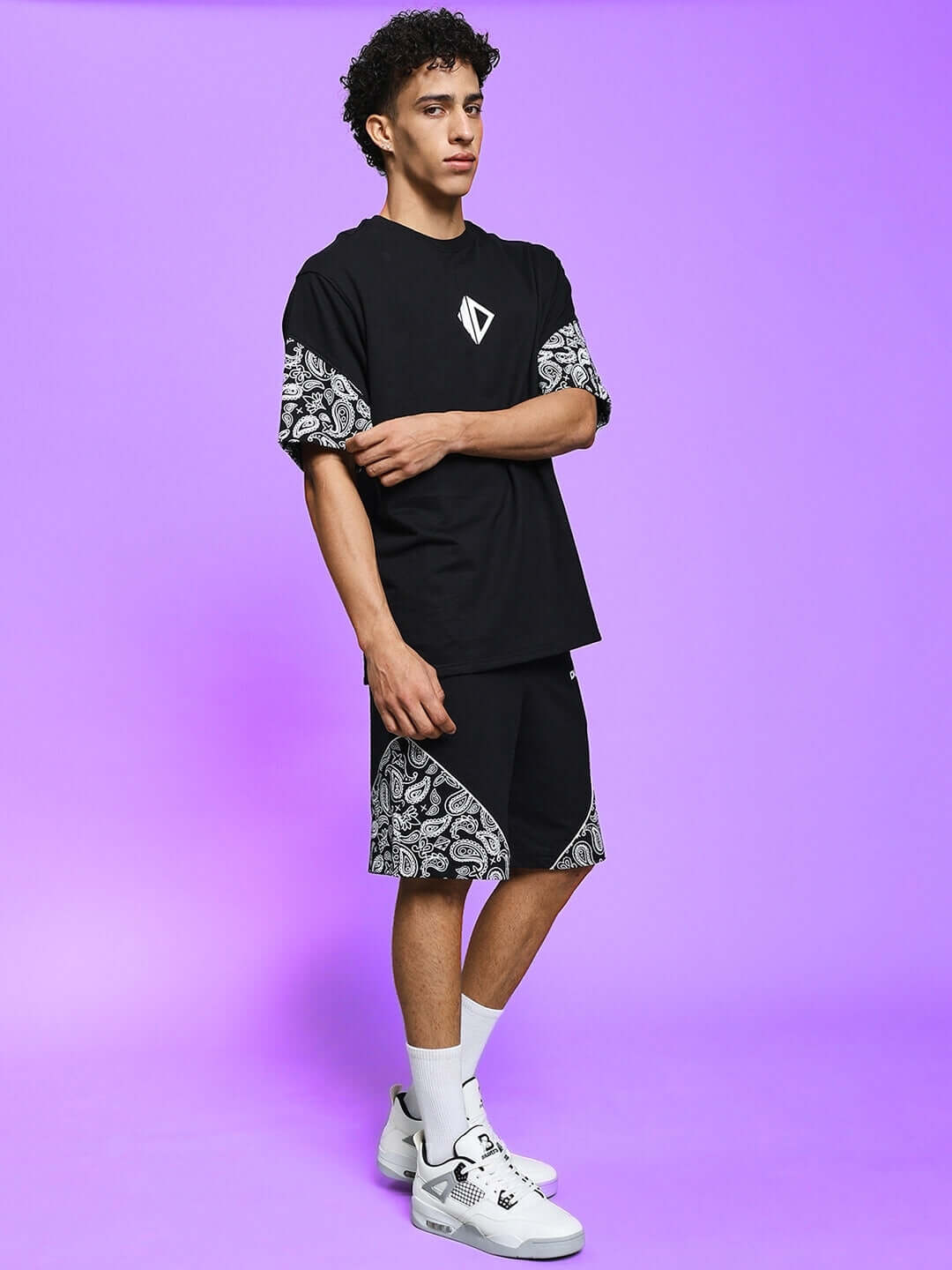 Model wearing CALVIN CO-ORD SET in black with patterned accents, made of premium cotton French terry lycra, against a purple background.
