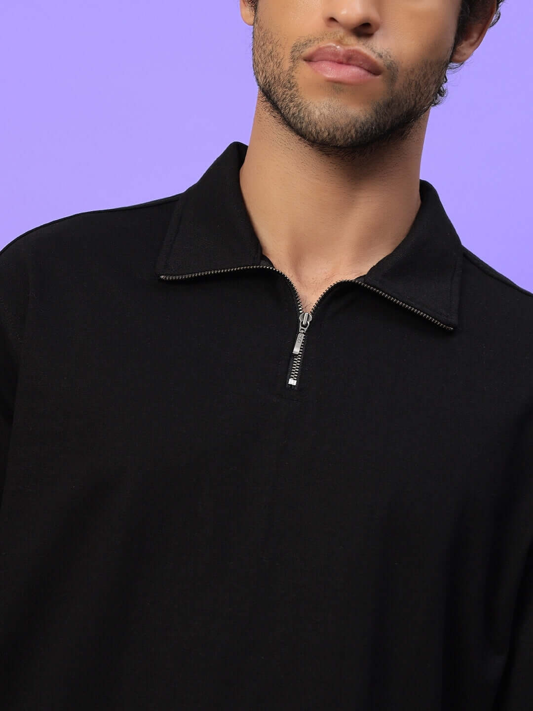 Model wearing Candid Oversized Sweatshirt in black showing half-zip design on a purple background