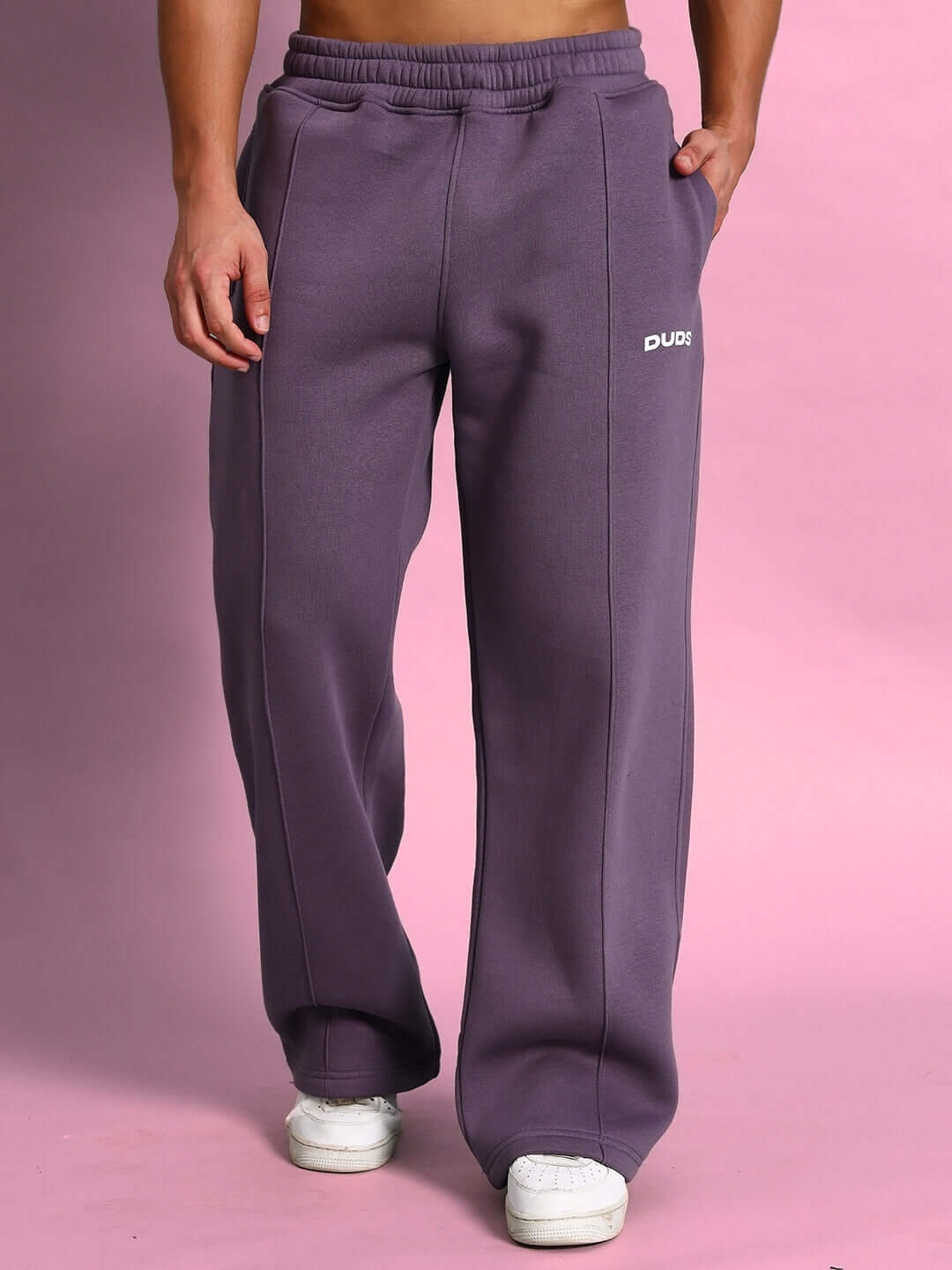 Model wearing CASPER COTTON FLEECE CO-ORD VIOLET joggers against pink background, highlighting comfort and streetwear style.