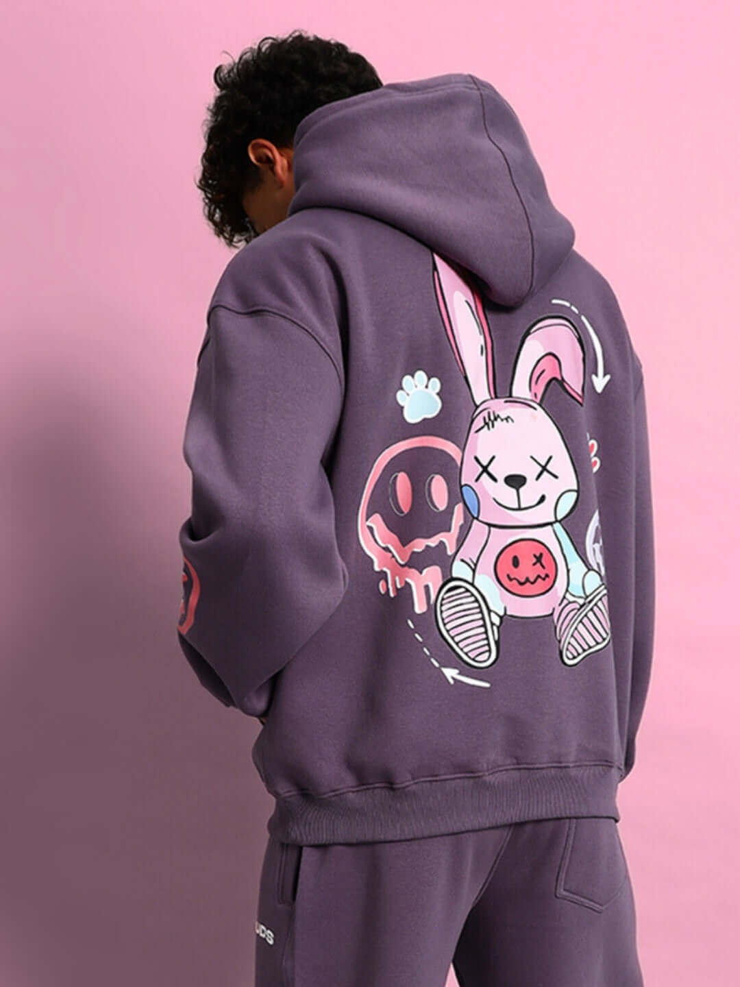 Person wearing a CASPER COTTON FLEECE HOODIE VIOLET with playful graphic design on the back, showcasing streetwear style.
