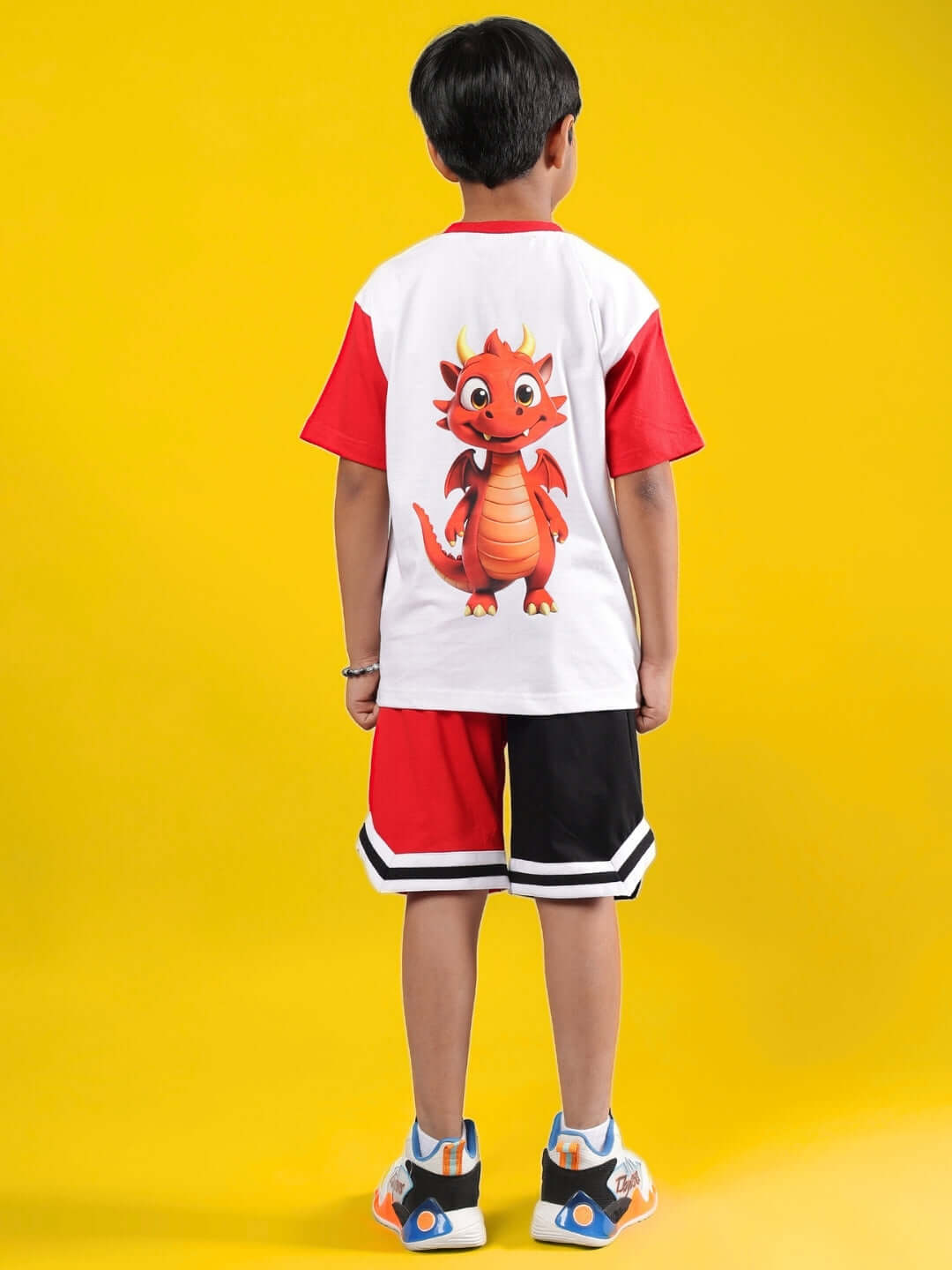 Child wearing CASSIE CO-ORD in white and red, featuring a dragon print on the back, with vibrant yellow background.