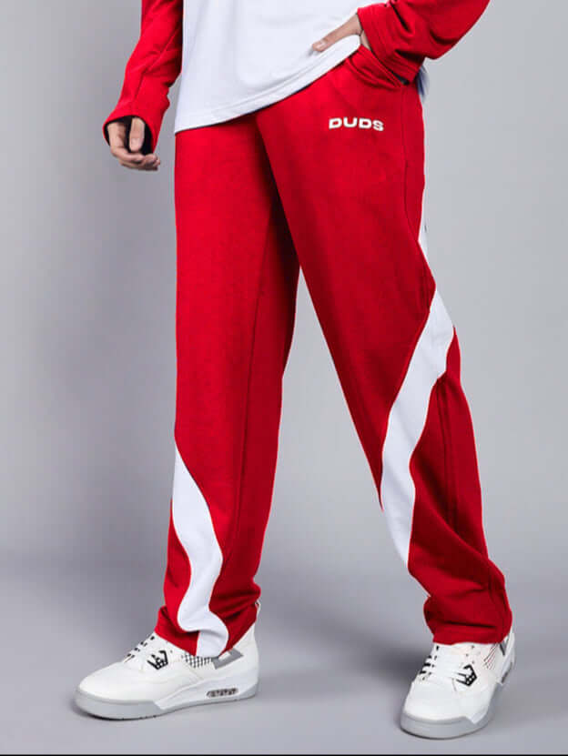Person wearing red and white relaxed fit jogger labeled 'DUDS', showcasing casual style with sneakers.