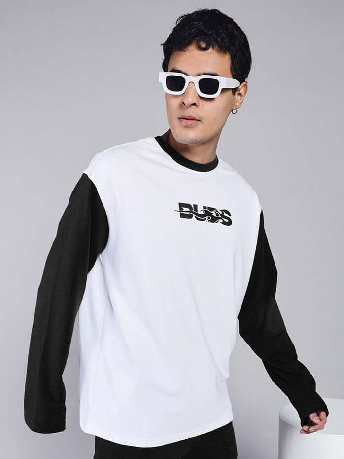 Model wearing Celestine Cool Sweatshirt in white with black sleeves, made of premium cotton French terry. Stylish casual wear with logo print.