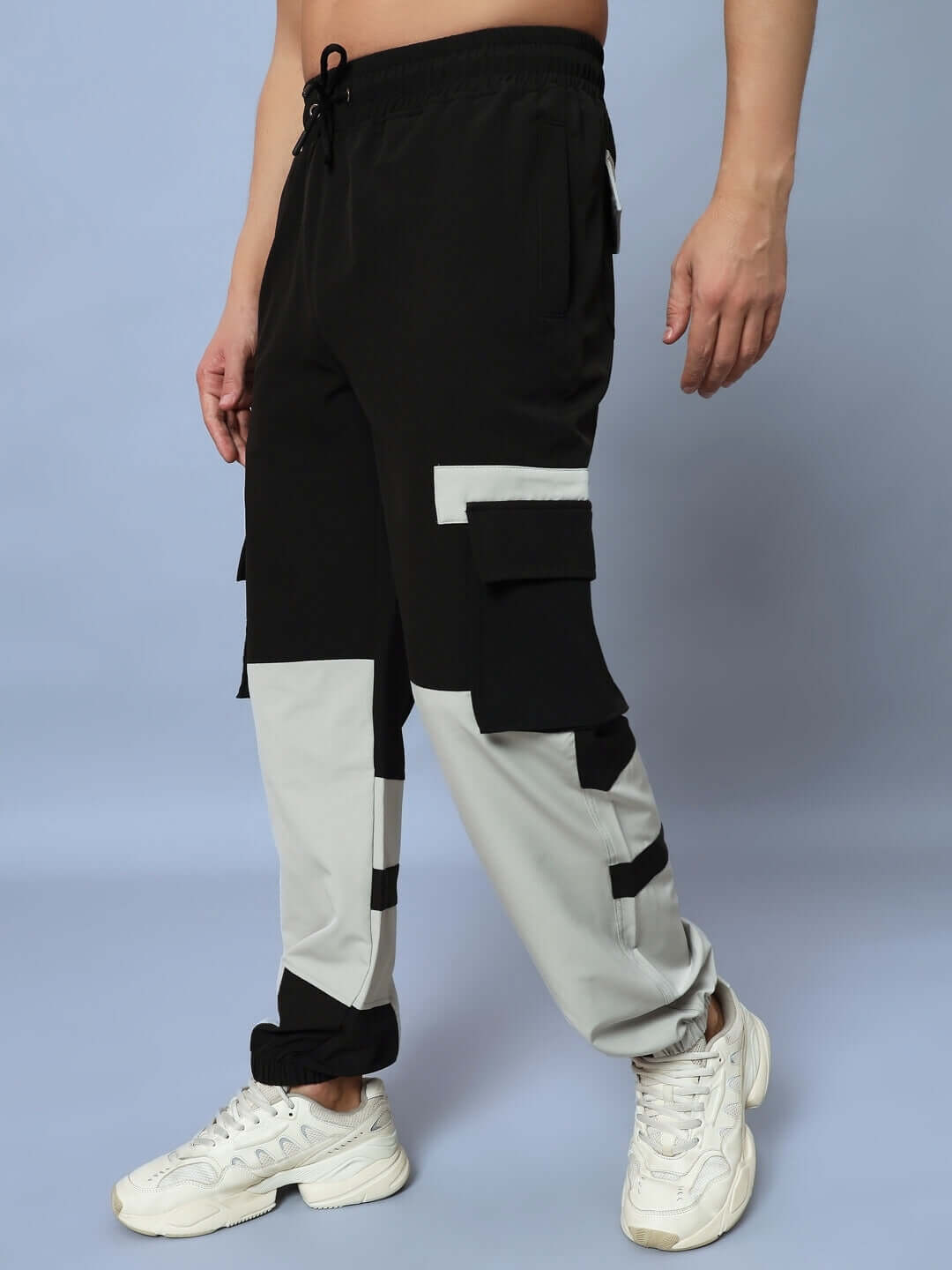 Man wearing CHALET RELAXED FIT CARGO PANTS BLACK GREY with sneakers, showing side pockets and relaxed style.