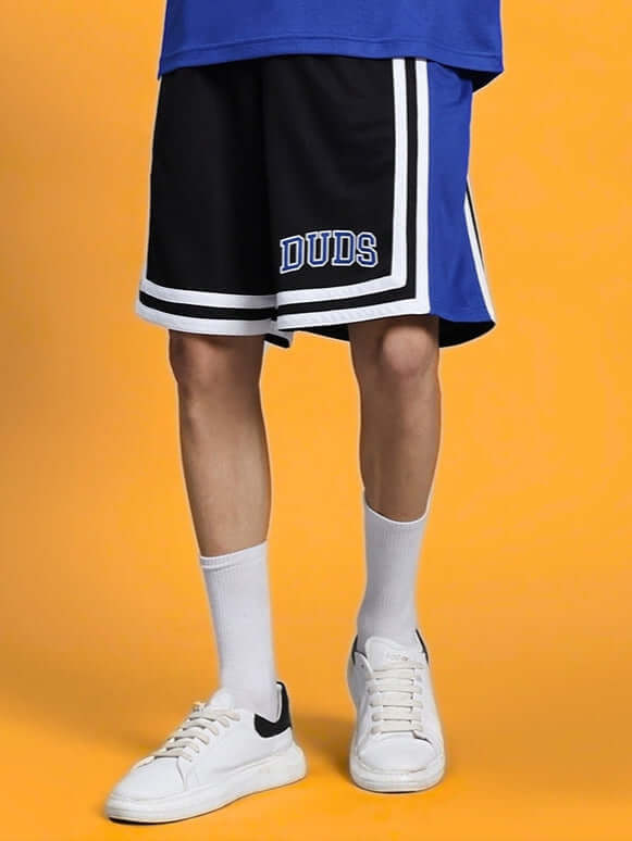 Model wearing Challenge Regular Fit Shorts in R Blue, featuring DUDS logo, available with custom fit option for prepaid orders.