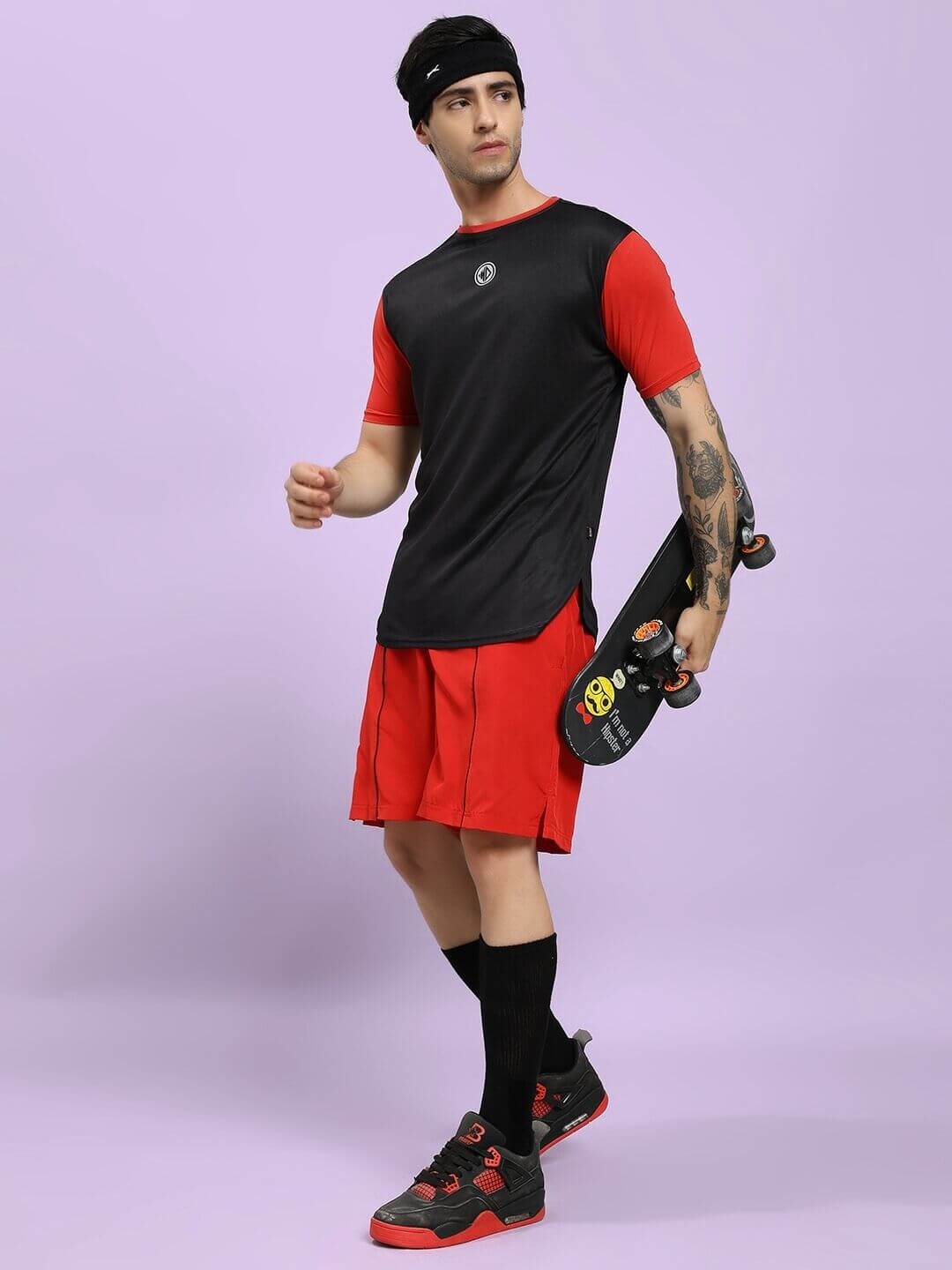 Athlete in CHAMPION ZONE FRONT PLATED SHORTS RED holding a skateboard on a lavender background