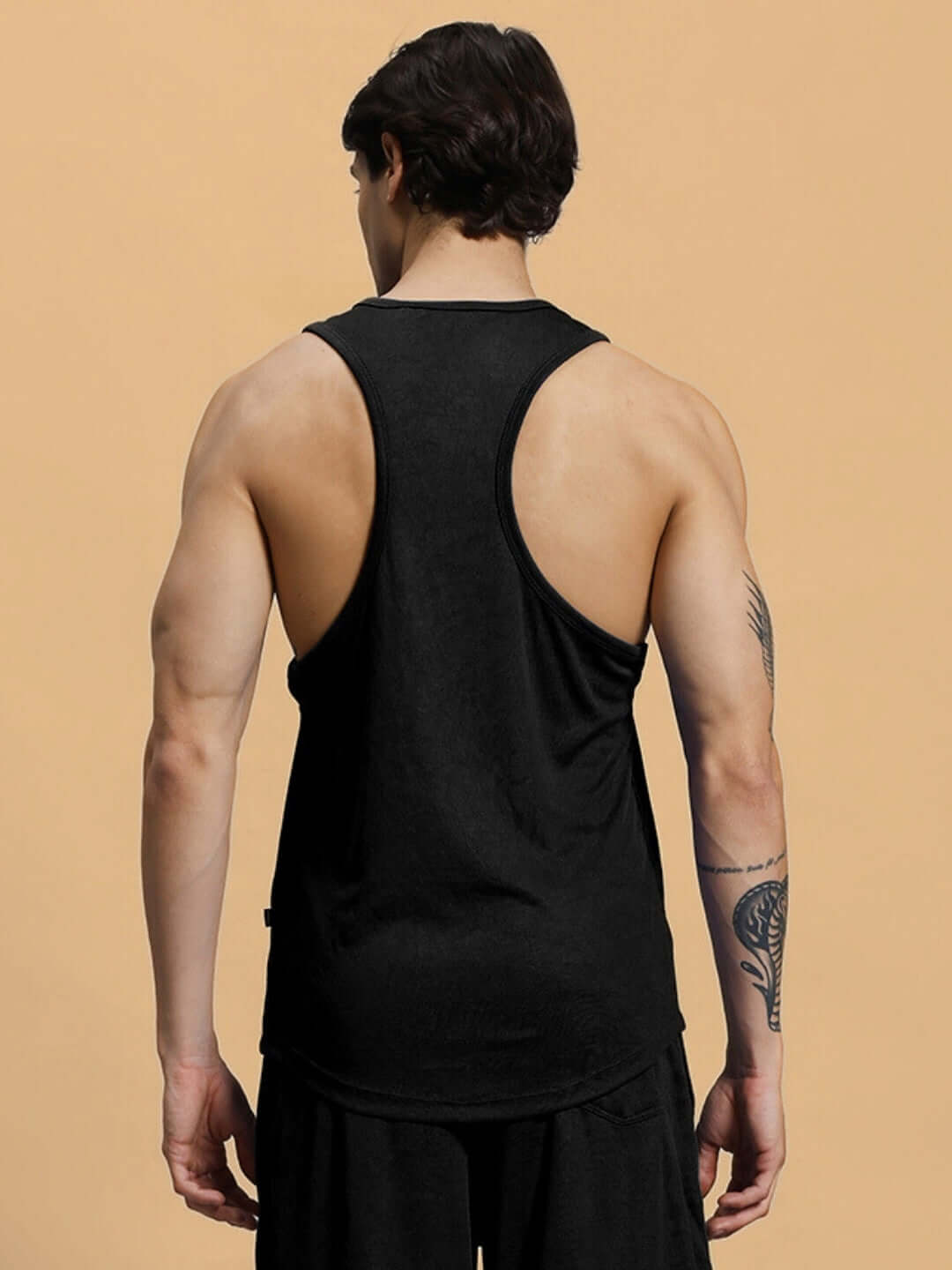 Back view of a male model wearing a CHANGE YOUR LOOKS black gym t-shirt showcasing muscle definition against a neutral background.