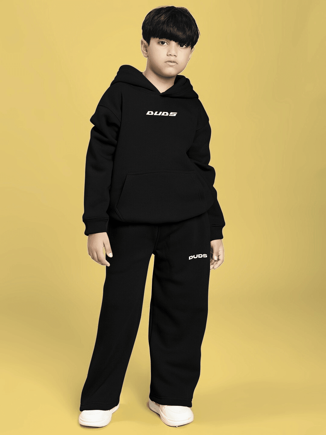 Child wearing CHARMING CARTOON DOGS FLEECE HOODIE FOR BOYS AND GIRLS BLACK, showcasing cute cartoon dog graphics, standing on yellow background.