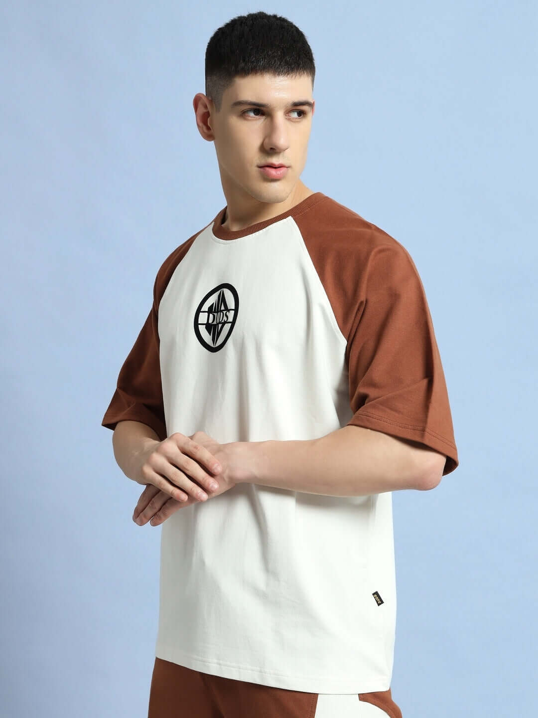 Model wearing oversized chestnut raglan t-shirt in off white and brown, made from premium cotton and elastane, 240 GSM, by Color By.