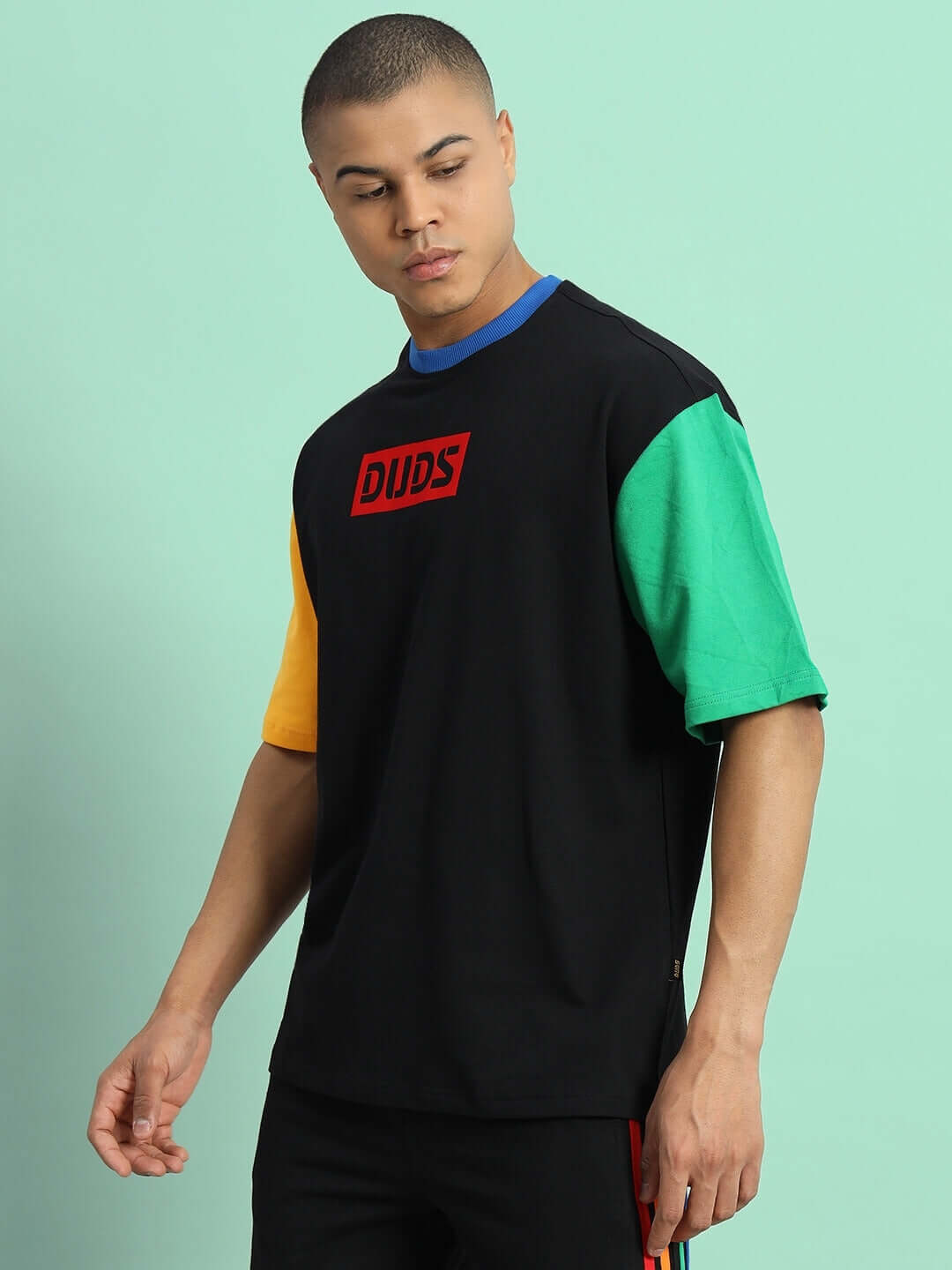 Chroma Color Blocked Oversized T-Shirt in black with colorful sleeves, made of premium cotton French terry, worn by a model against a mint background.