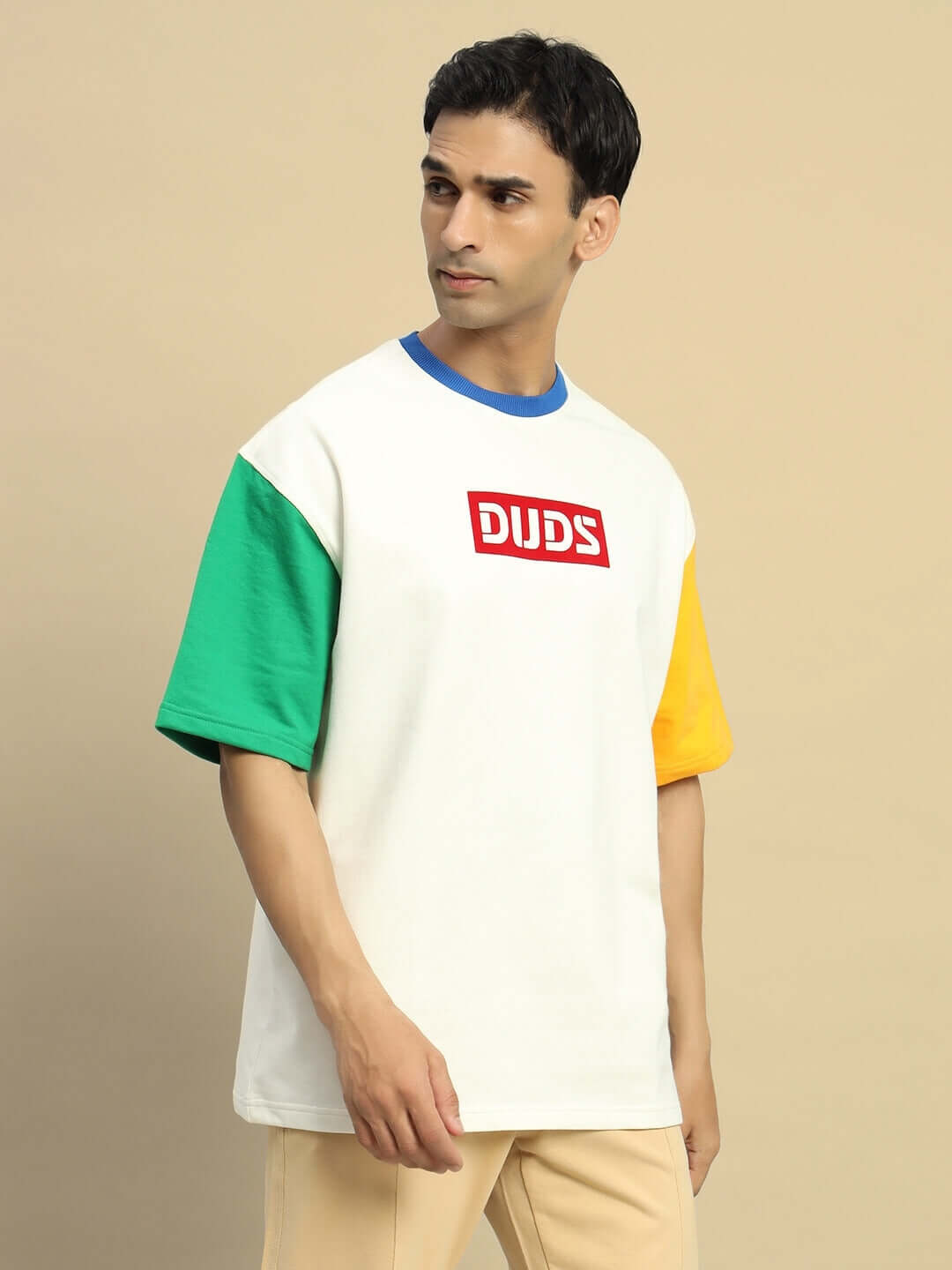 Model wearing CHROMA Color Blocked Oversized T-shirt in Off White with eco-friendly cotton blend, showcasing green and yellow sleeve accents.