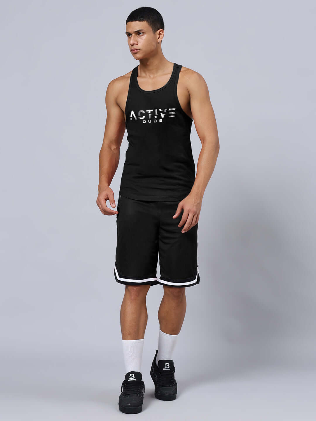 Model wearing CHRONIC REGULAR FIT SHORTS BLACK, showcasing athletic casual style with tank top and sneakers.