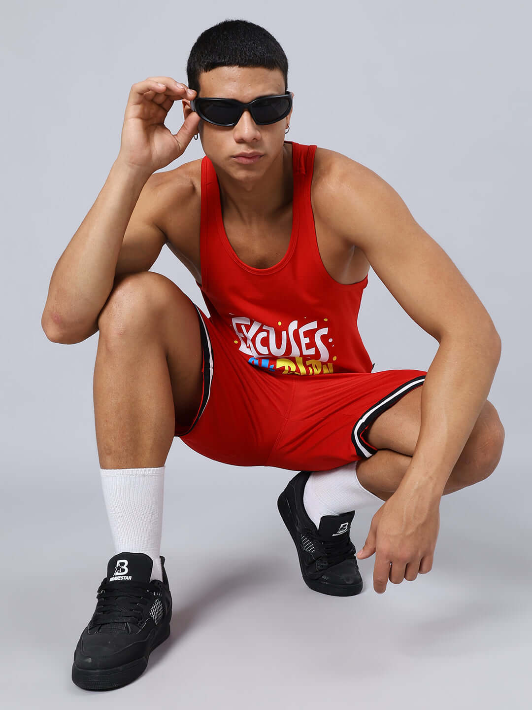 Model wearing CHRONIC REGULAR FIT SHORTS in red with sporty design, custom fit option available, posing in stylish sunglasses.