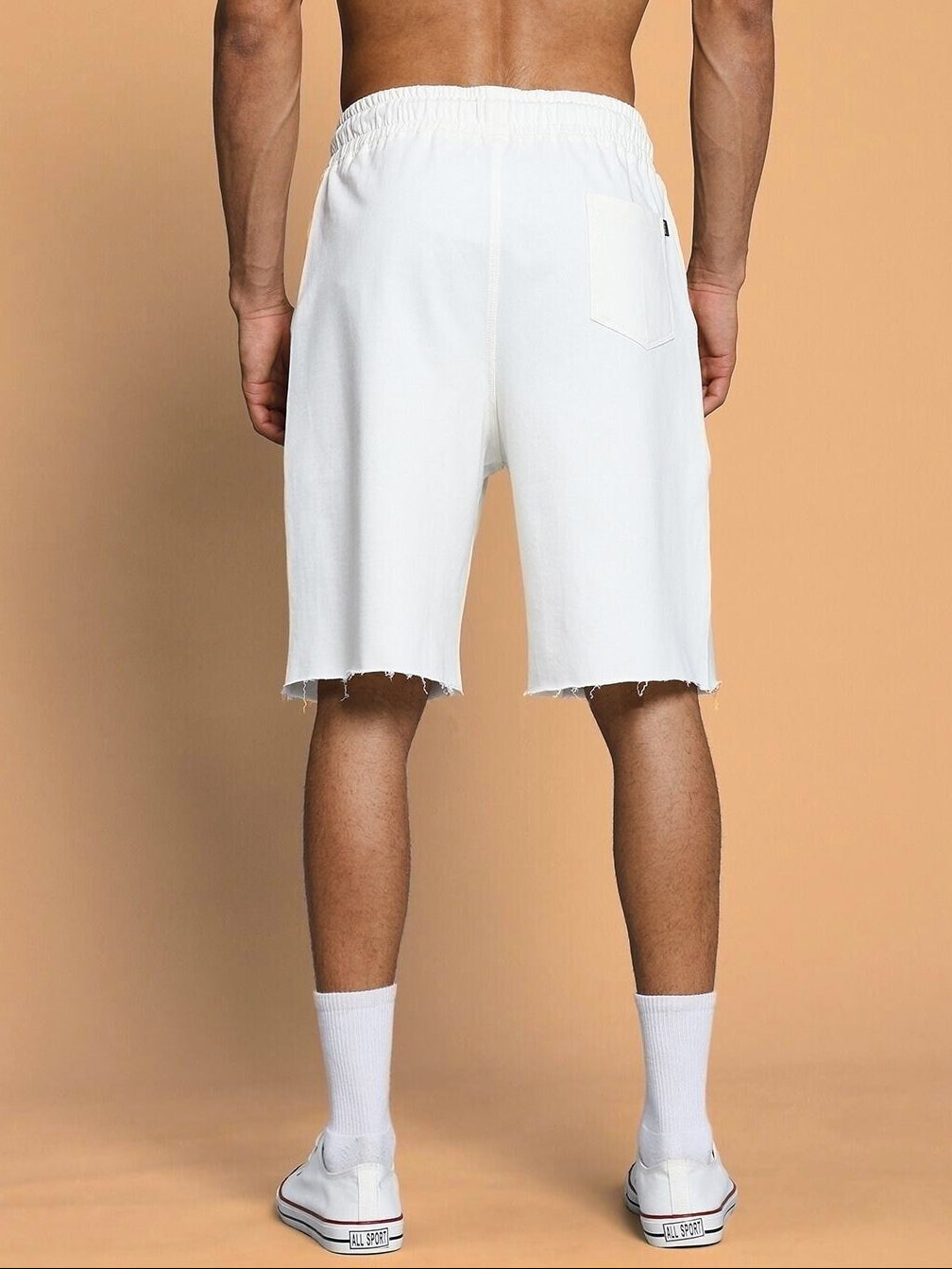 Back view of CLOUD PRINTED RELAXED FIT SHORTS OFF WHITE on model, showing elastic waistband and raw edge detailing, perfect for casual style.