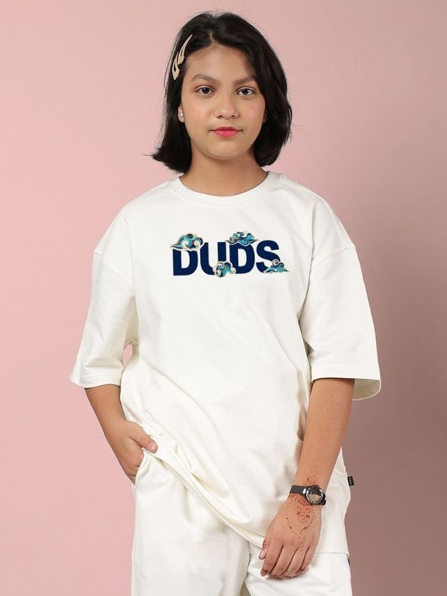 Girl wearing CLOUD PRINTED OVERSIZED T-SHIRT FOR BOYS AND GIRLS OFF WHITE with playful cloud design, showcasing casual style.