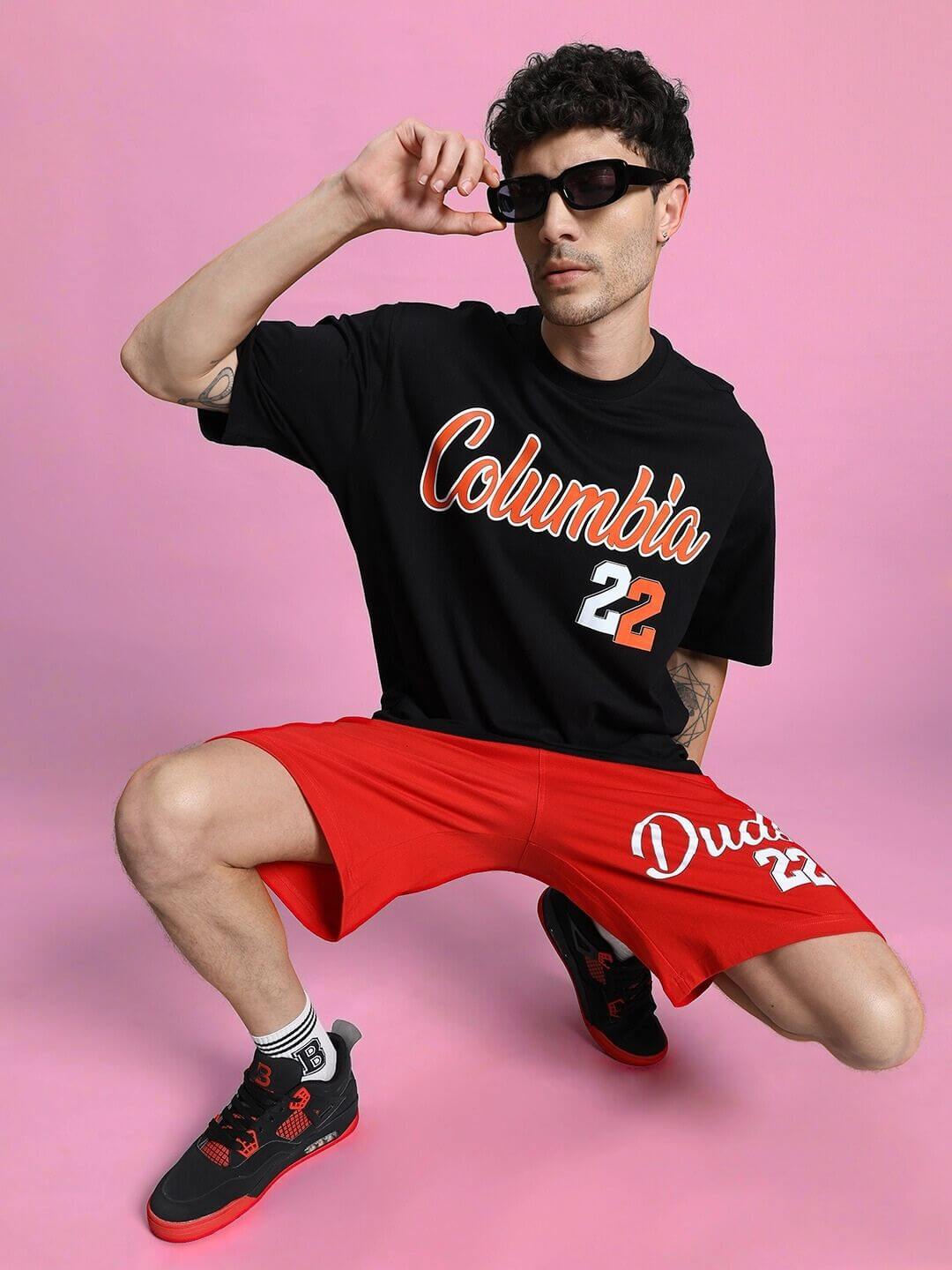 COLUMBIA 22 REGULAR FIT SHORTS RED worn by model in black shirt and sunglasses, showcasing athletic style for summer activities.