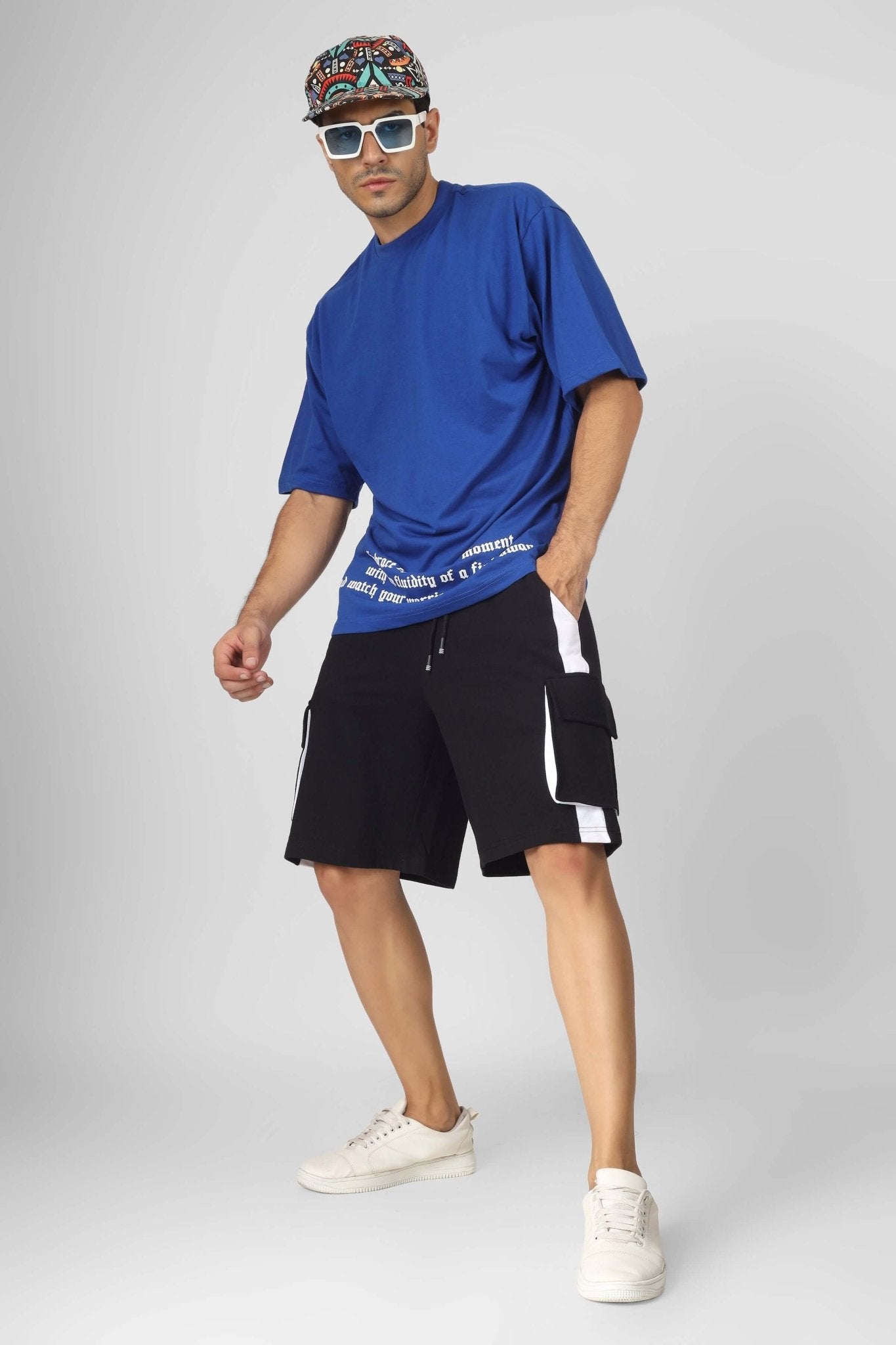 Model wearing CONTRA REGULAR FIT CARGO SHORTS BLACK WHITE with a casual blue shirt and sneakers, embodying streetwear style.