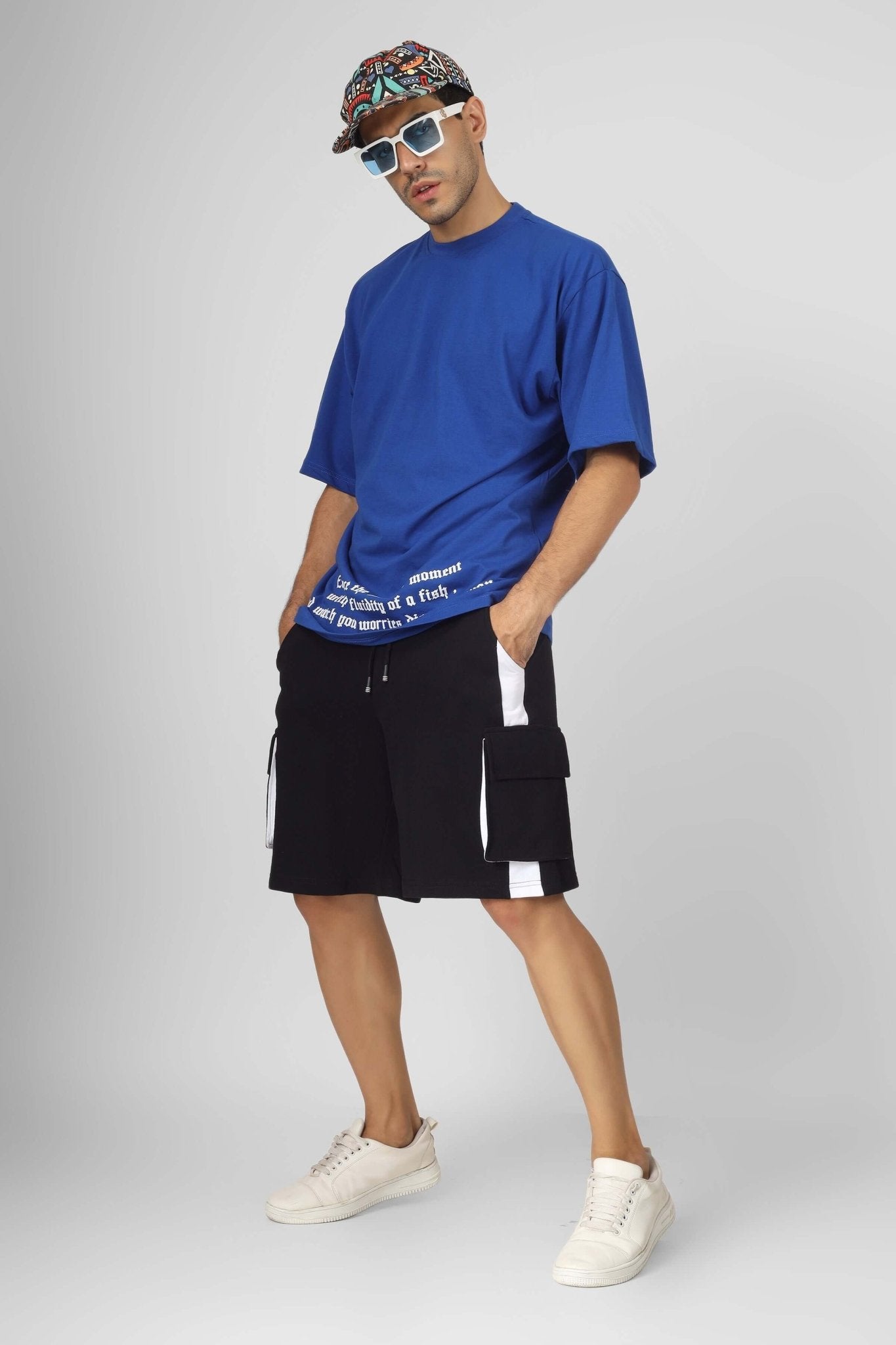 Model wearing CONTRA REGULAR FIT CARGO SHORTS BLACK WHITE with blue T-shirt and accessories, showcasing bold streetwear style.