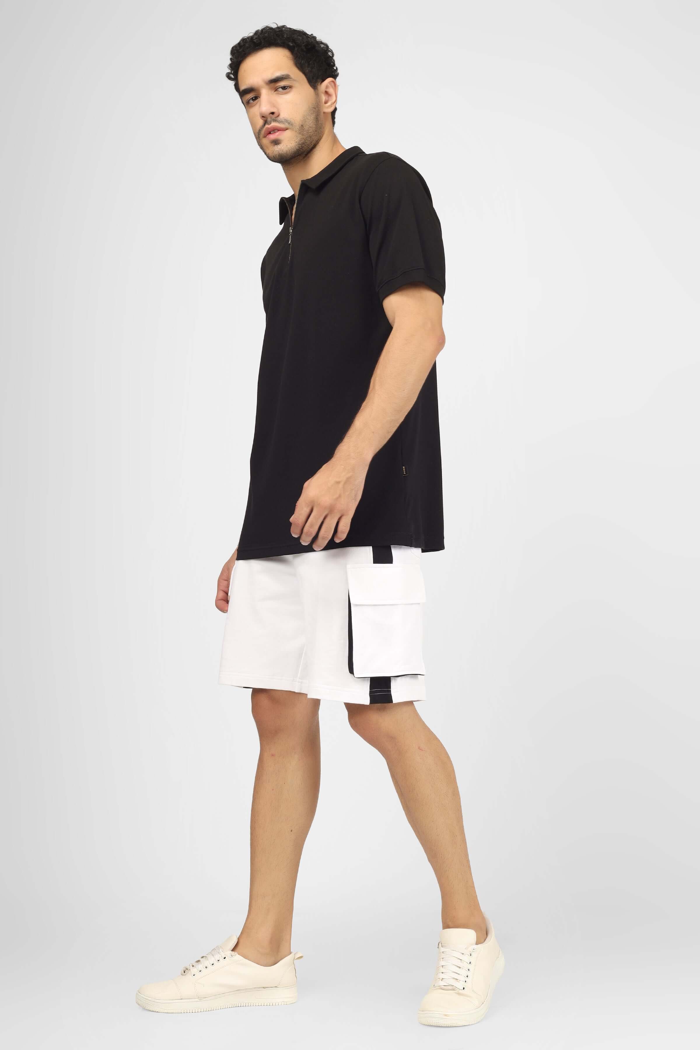 Man wearing CONTRA regular fit cargo shorts in white and black, paired with a black polo shirt and white sneakers.