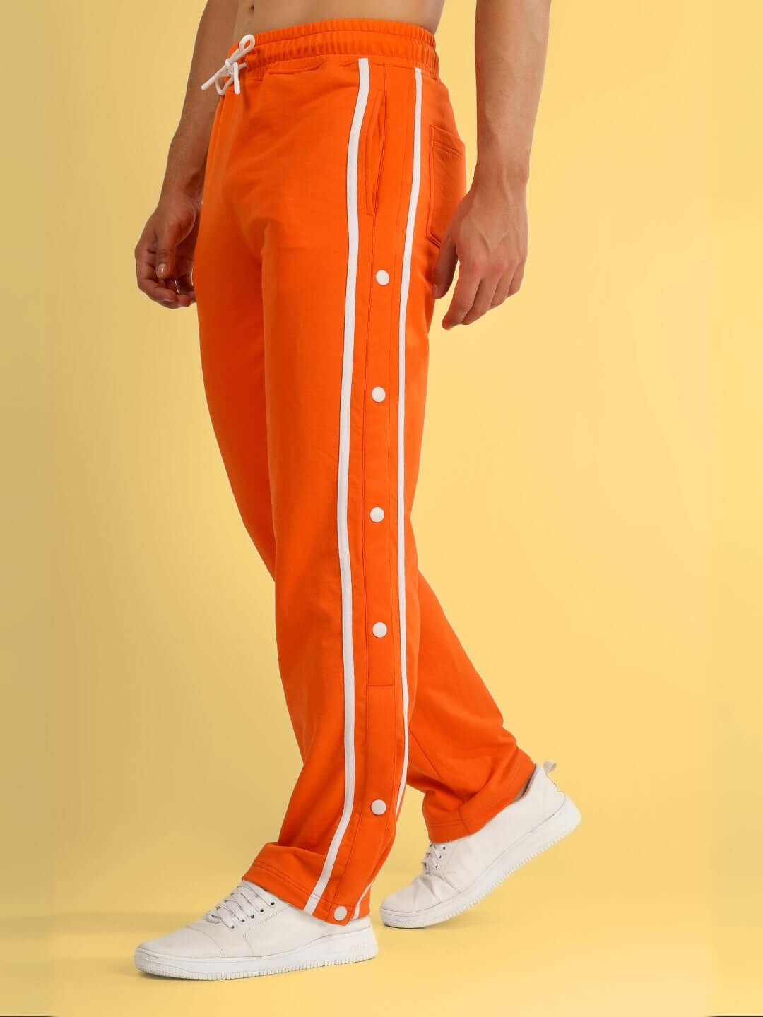 Model wearing orange contrast panel jogger with white sneakers, showcasing side buttons, made by DUDS.
