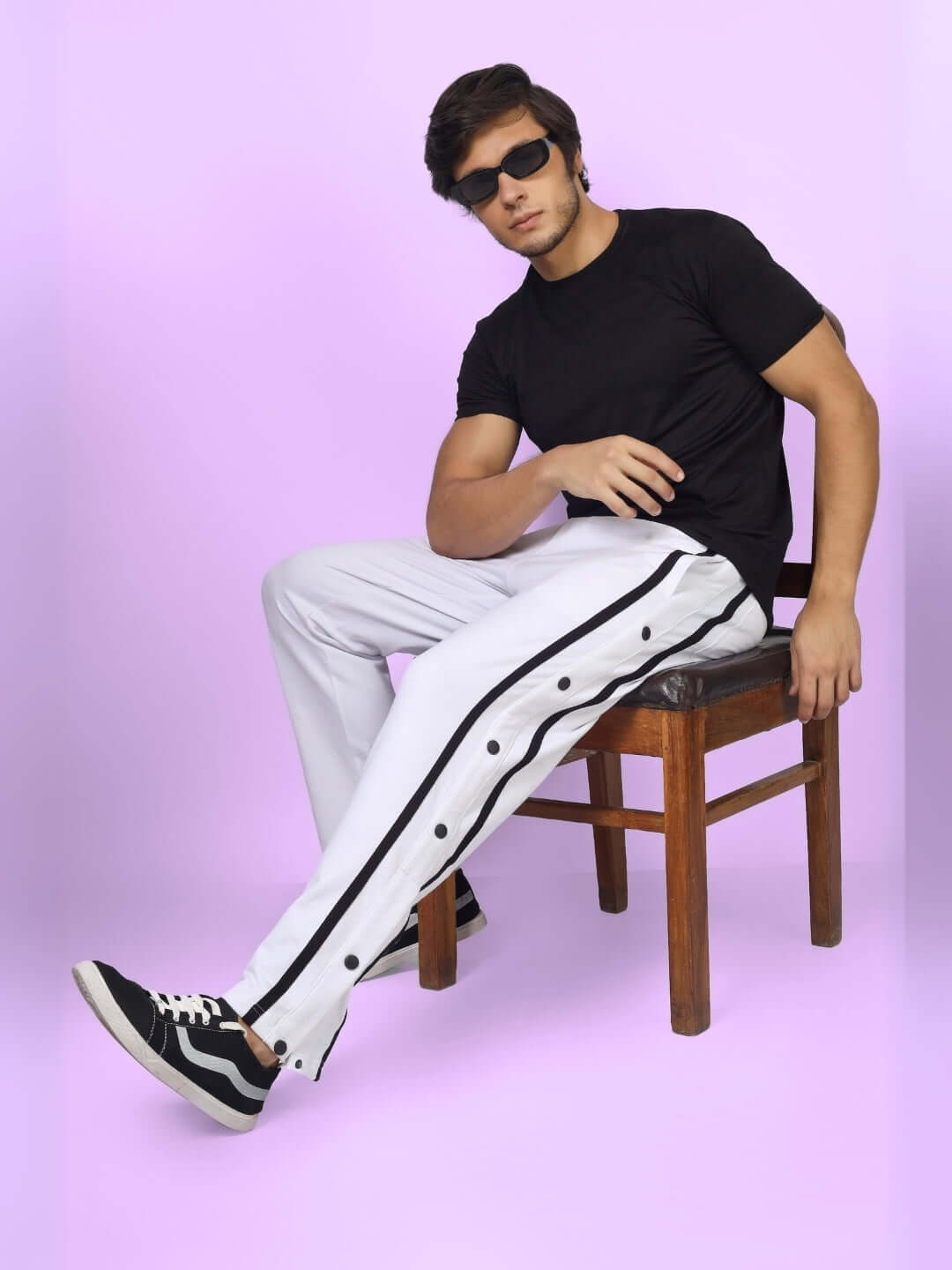 Model wearing contrast panel joggers in white, showcasing custom fit option with black side detailing, seated on chair against purple backdrop.