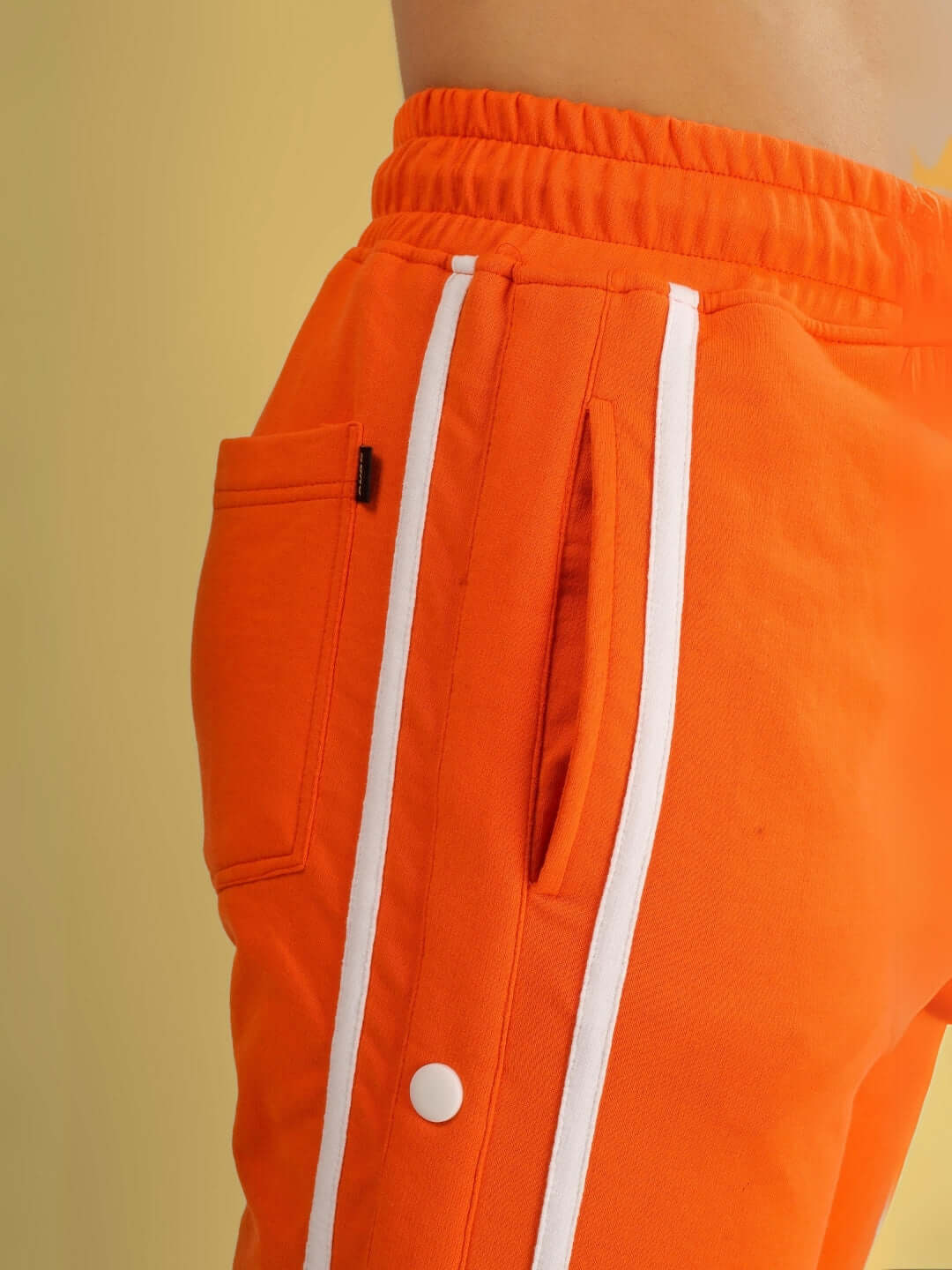 Close-up of orange contrast panel jogger with white stripes and pocket detail, emphasizing style and craftsmanship.