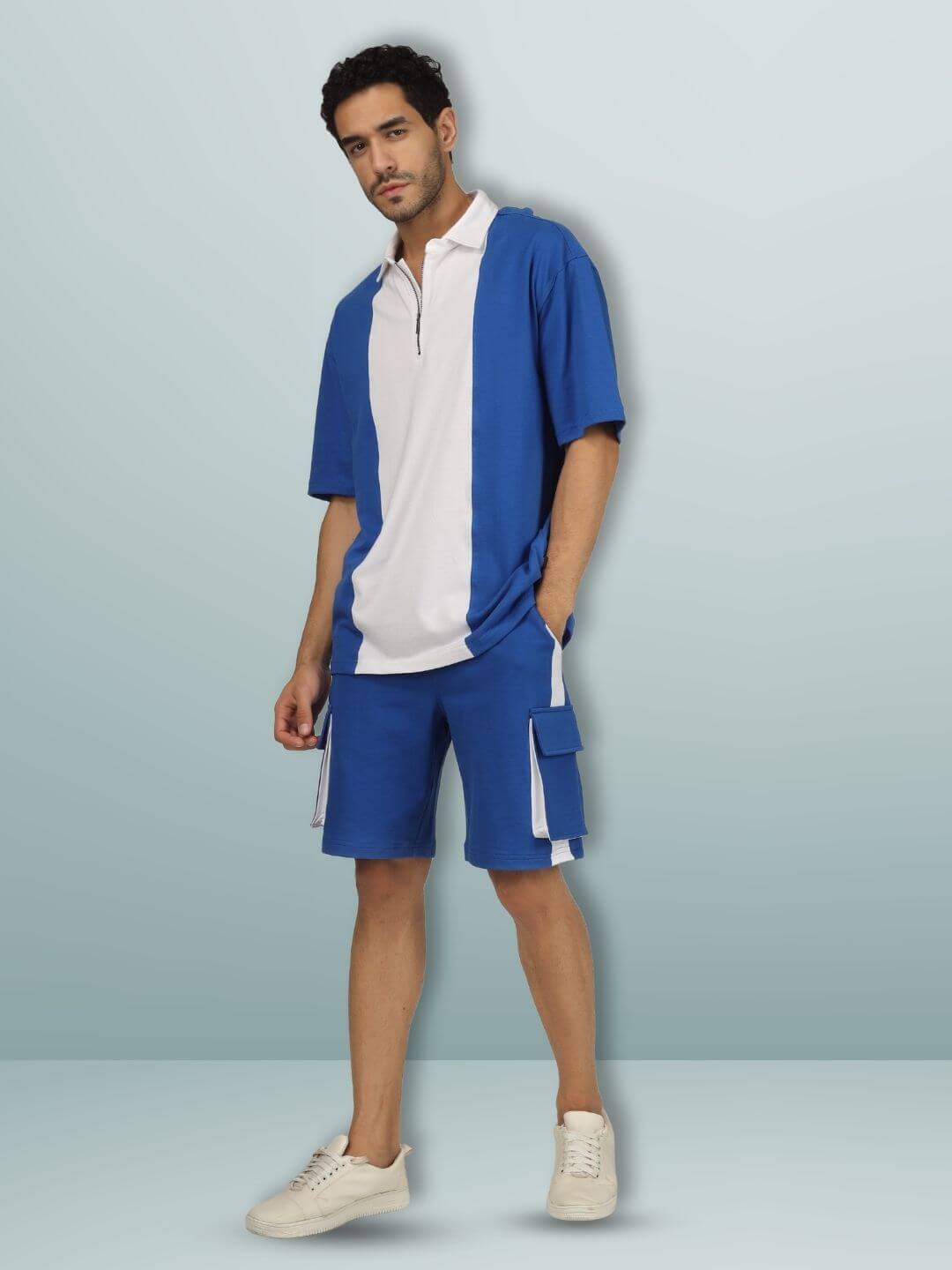 Model wearing oversized blue and white contrast polo with zipper, styled with blue shorts, showcasing half sleeves and casual fit.