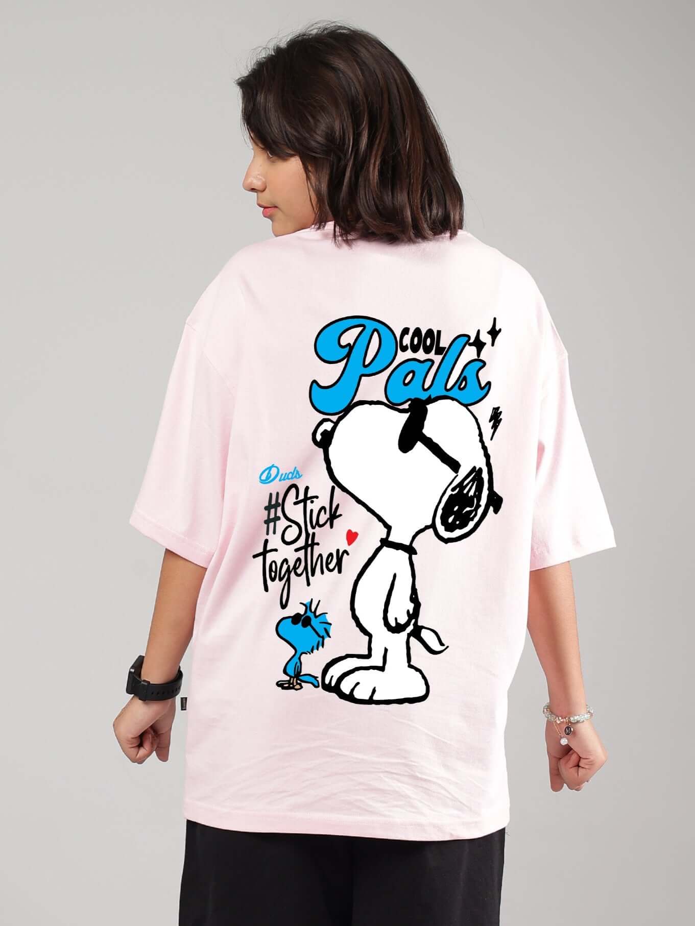 Person wearing COOL PALS pink oversized t-shirt for boys and girls with cartoon graphics on the back.