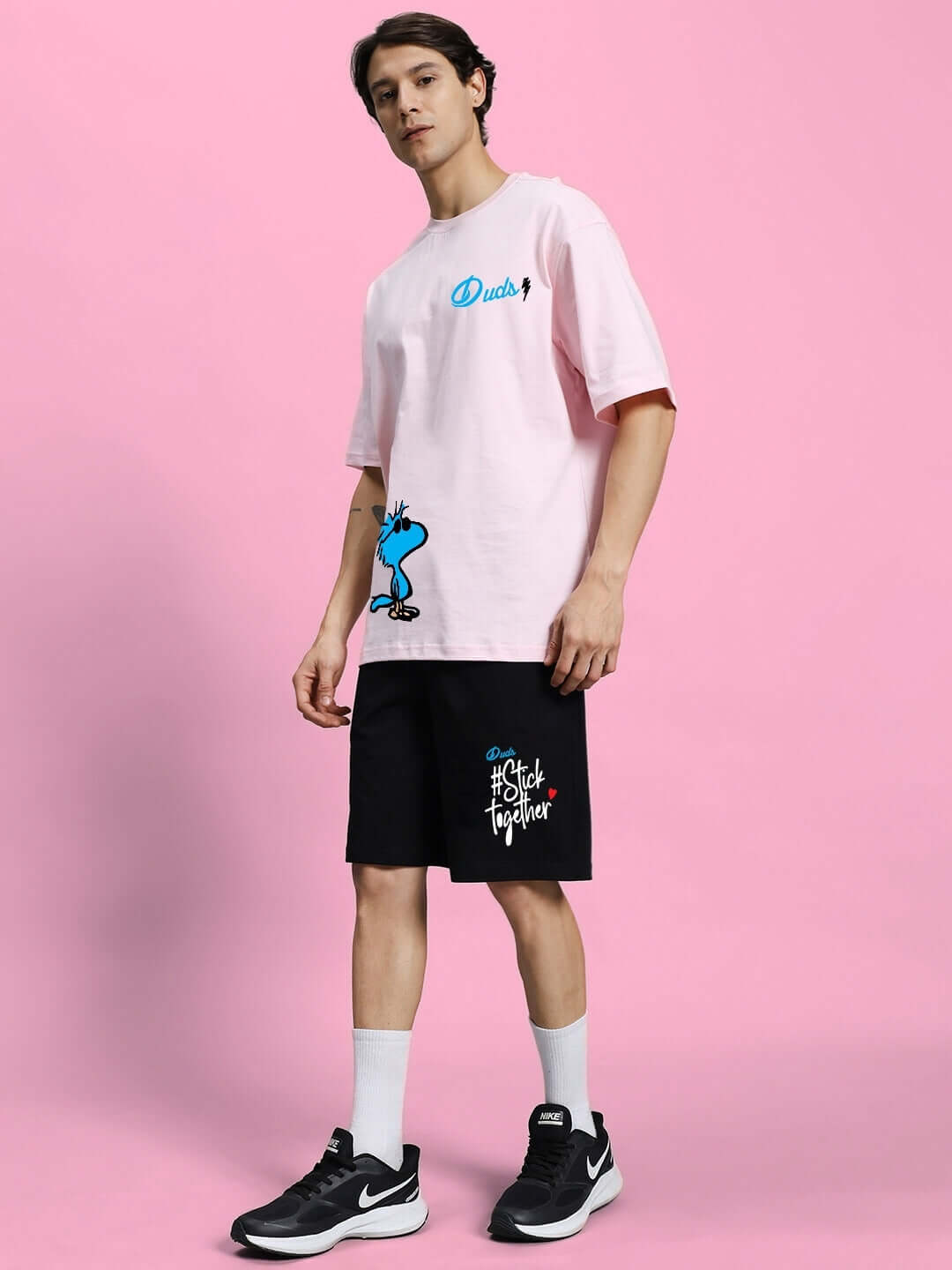Model wearing COOL PALS SUMMER CO-ORD SET PINK BLACK with pink oversized t-shirt and black shorts on pink background.
