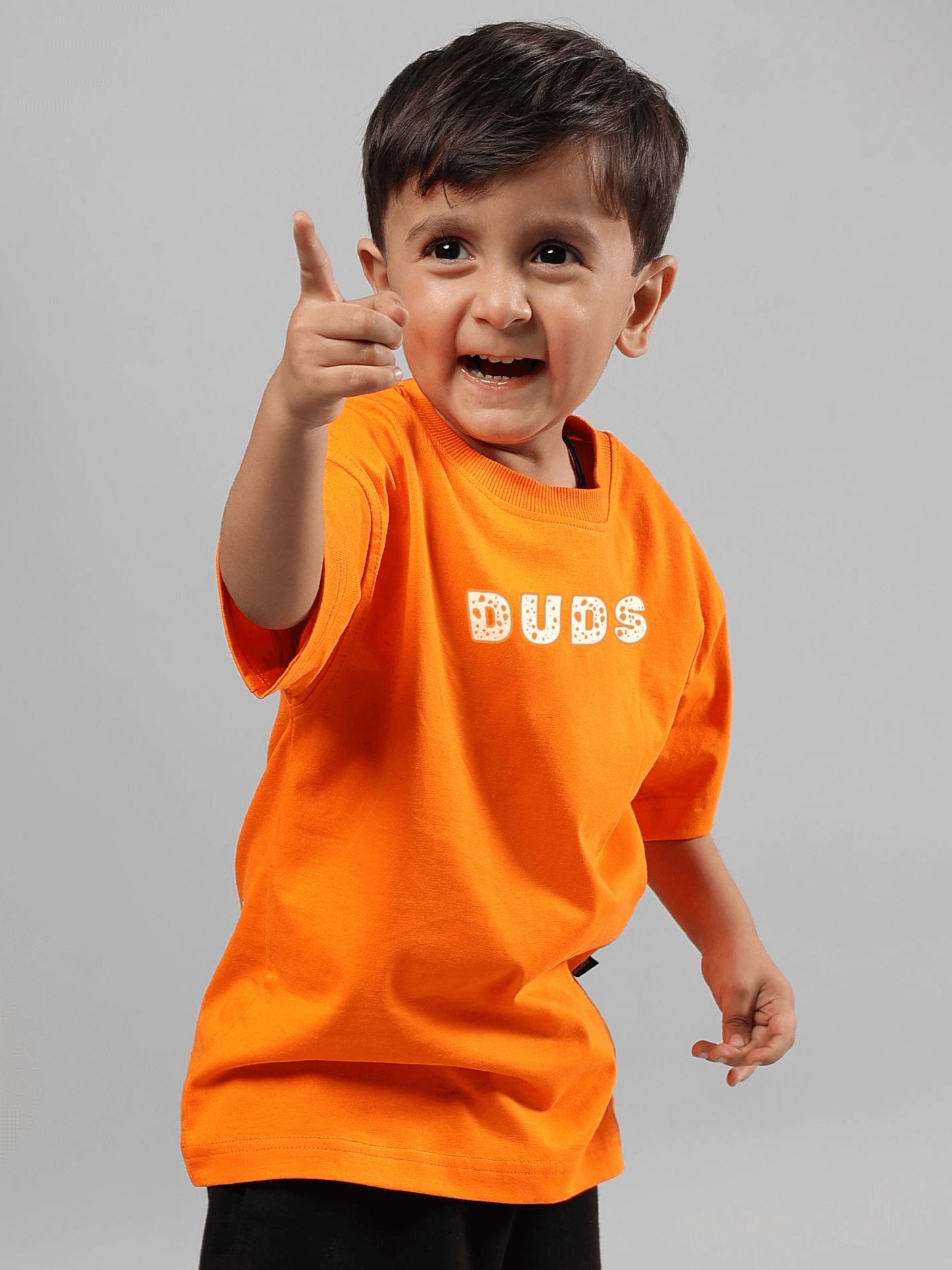 Boy wearing orange 'DUDS' Courage Toon T-shirt, smiling and pointing, ideal for boys and girls. Comfortable made-to-order shirt.