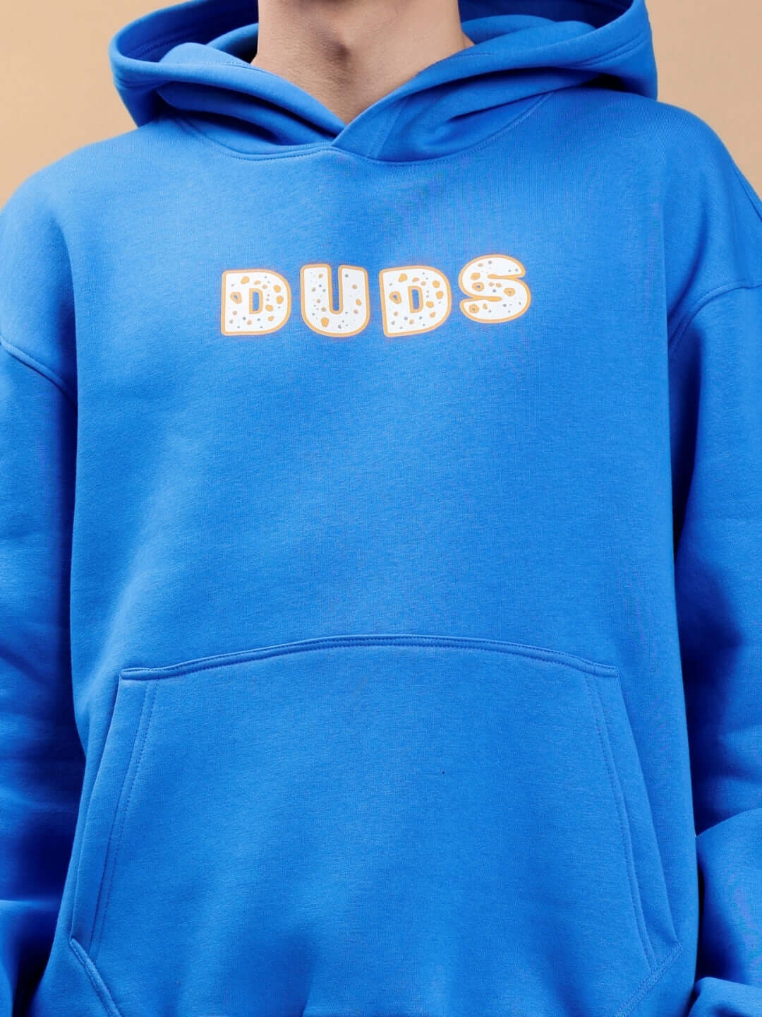 Person wearing a royal blue oversized hoodie with 'DUDS' text design, highlighting casual streetwear style.