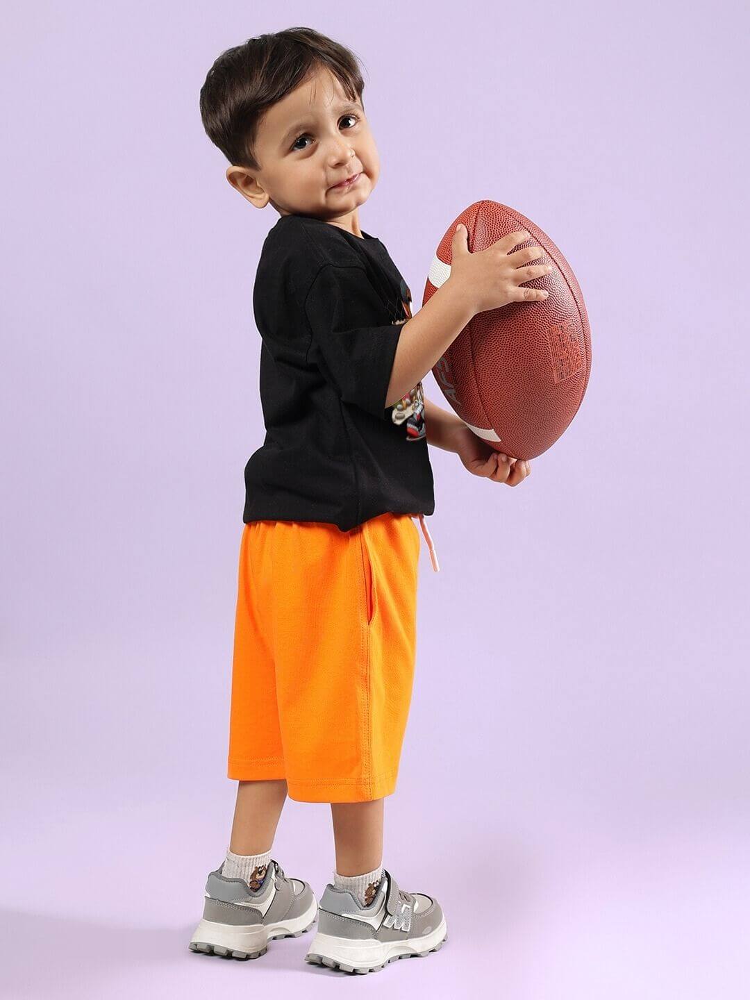 Child wearing CRAZY RAPPER CO-ORD FOR BOYS GIRLS AND BLACK-ORANGE holding a football, showcasing bold fashion and comfort.