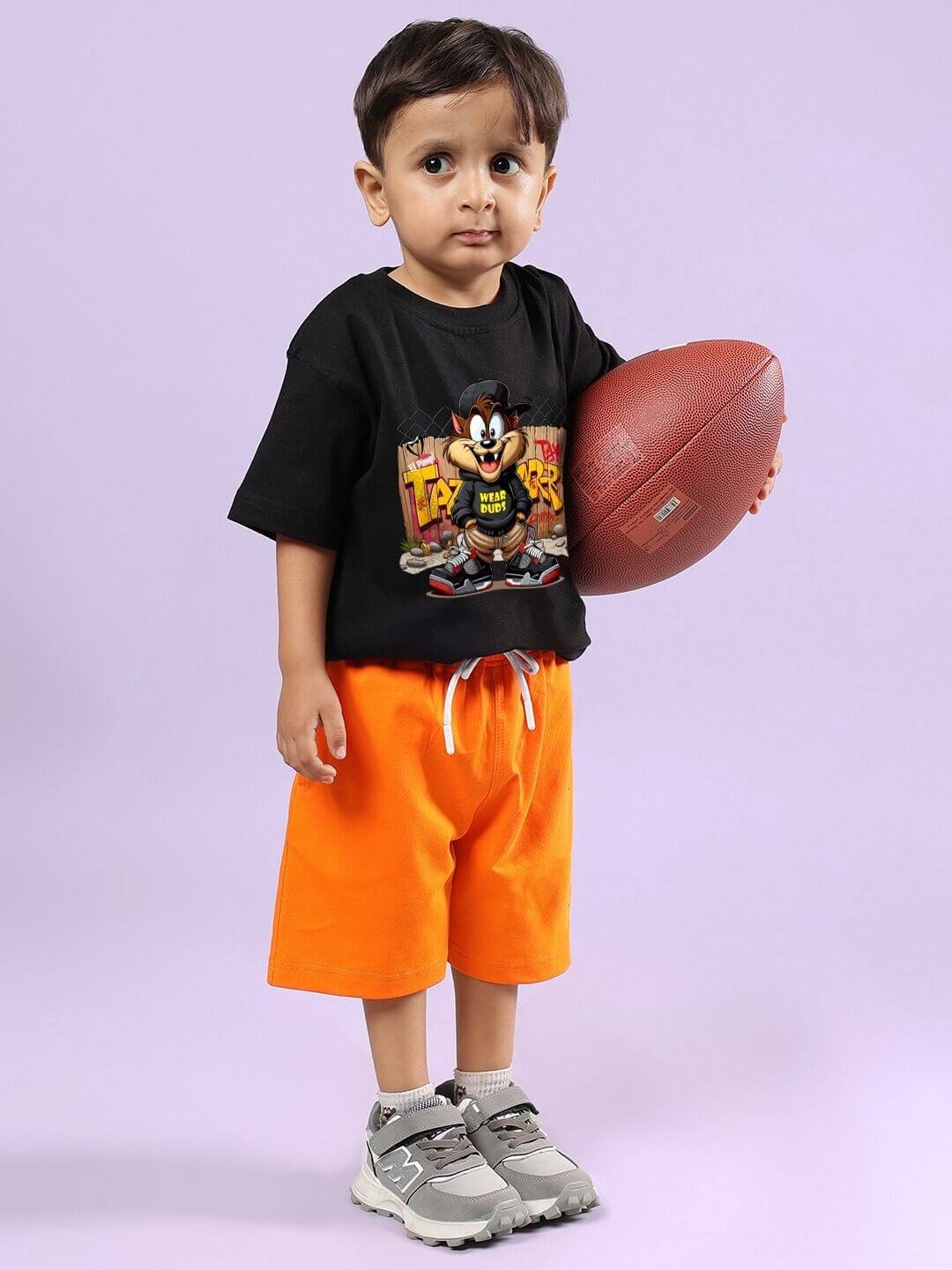 Child wearing Crazy Rapper black and orange co-ord set holding a football, showcasing urban fashion for kids.