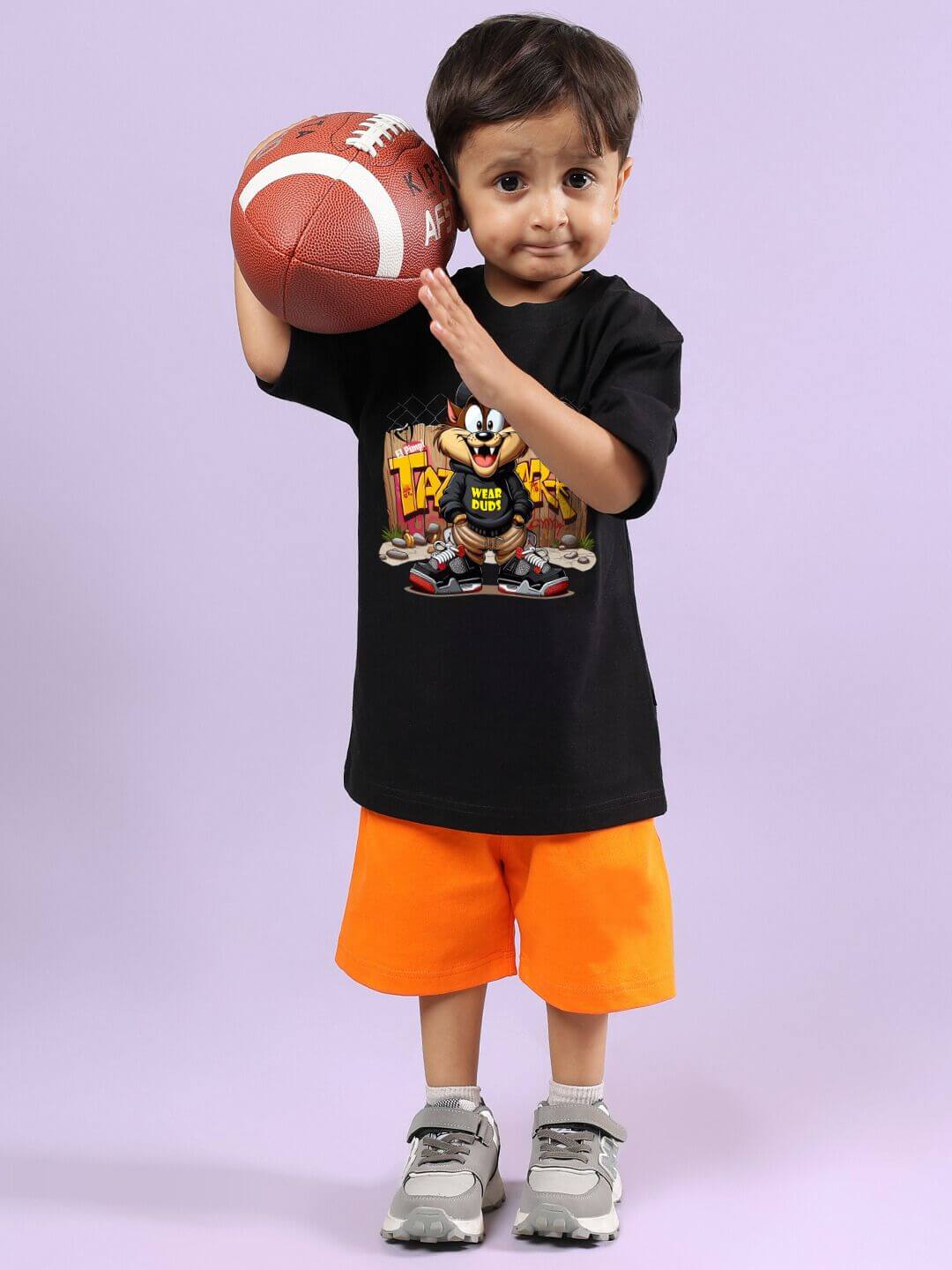Young boy wearing black and orange Crazy Rapper co-ord set holding a football, showcasing urban street-style fashion for kids.