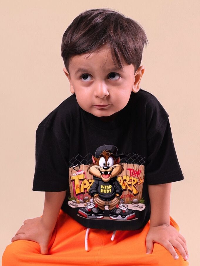 Young boy wearing black Crazy Rapper t-shirt with cartoon design, posing casually against a neutral background.