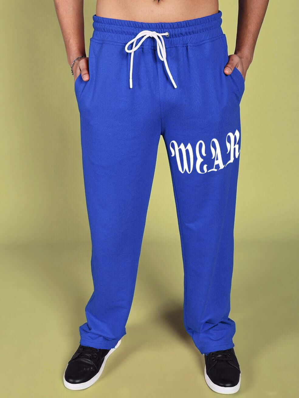 Model wearing crimson relaxed fit jogger in blue with elastic waistband and drawstring, featuring bold text design on left leg.