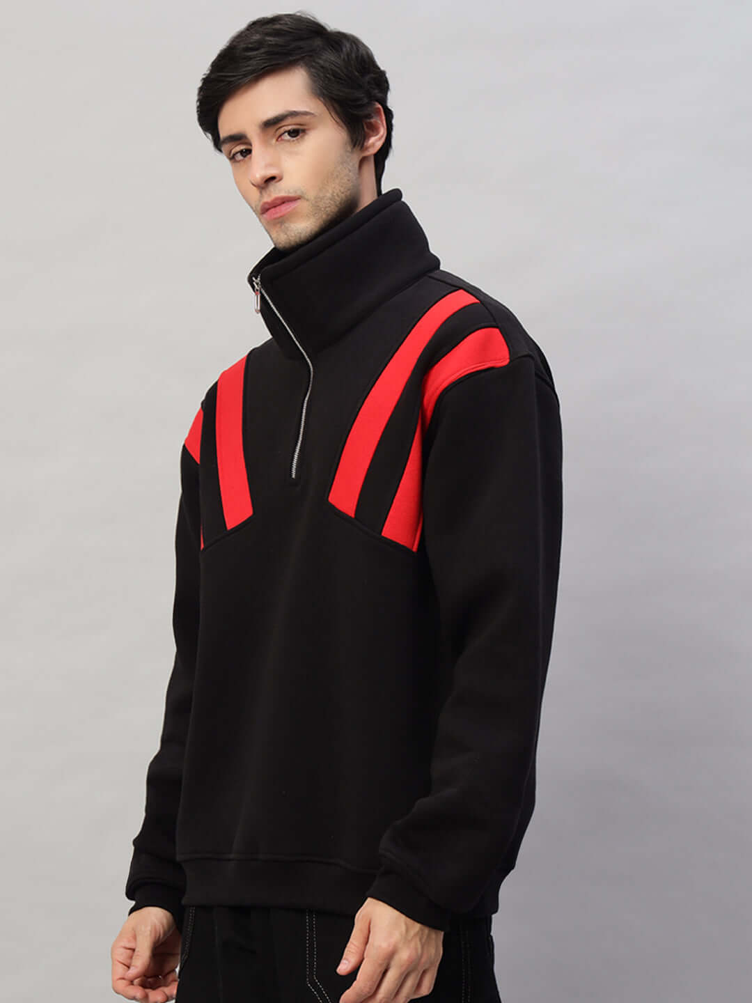 Man wearing black and red crossbar fleece colorblock jacket with high collar, showcasing fashionable outdoor wear for men.