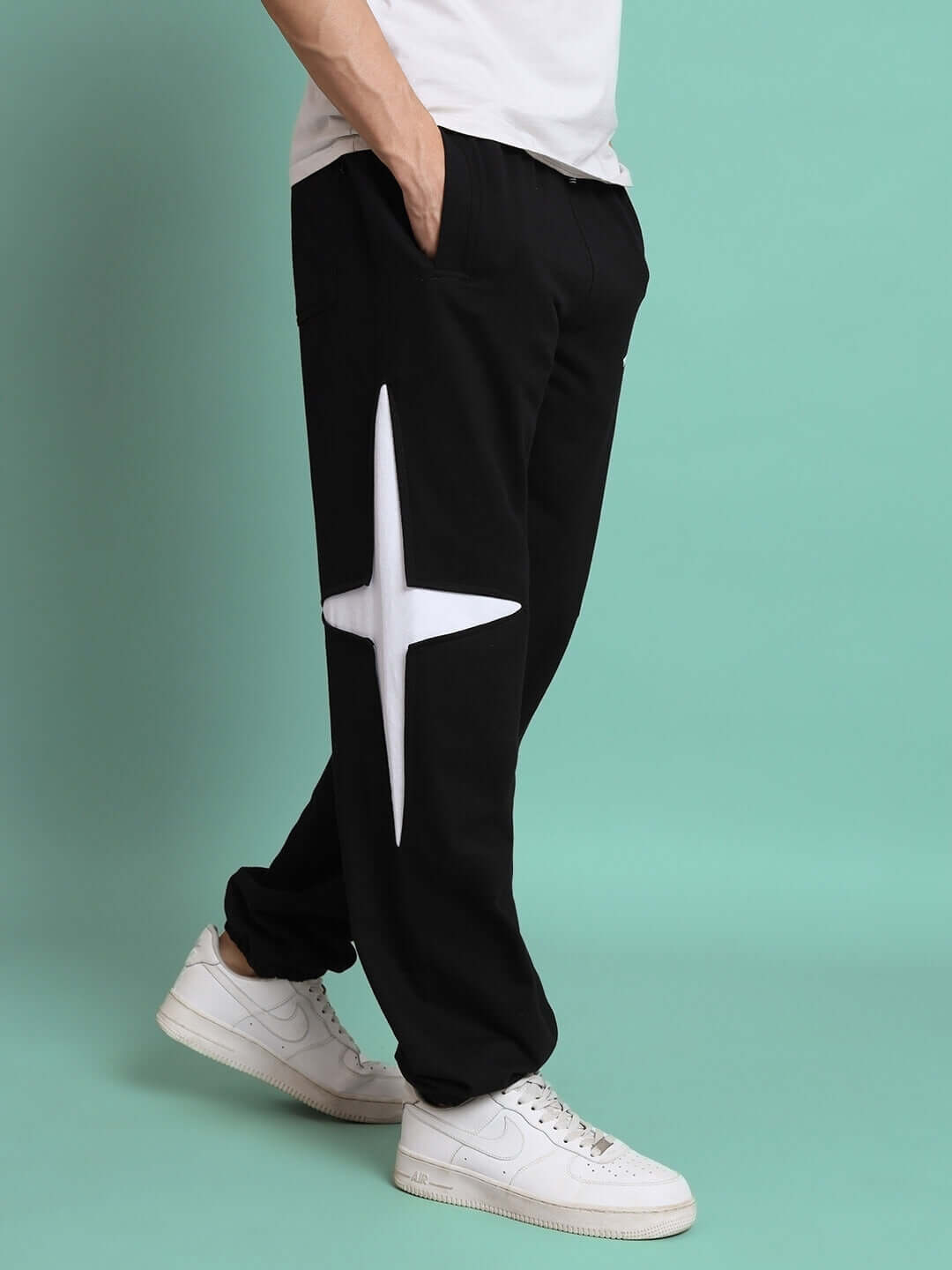 Black jogger pants with white star detail, styled with white sneakers, perfect for casual wear and available for custom fit.