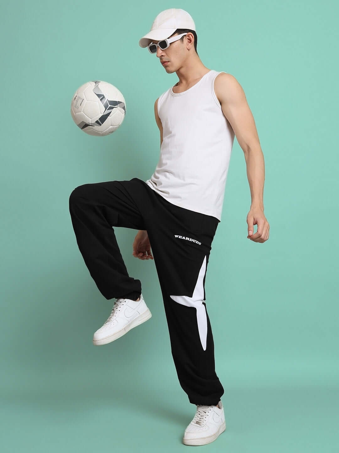 Man wearing CROSSED STAR JOGGER in black, performing a soccer trick, showcasing tailored fit and style by DUDS.