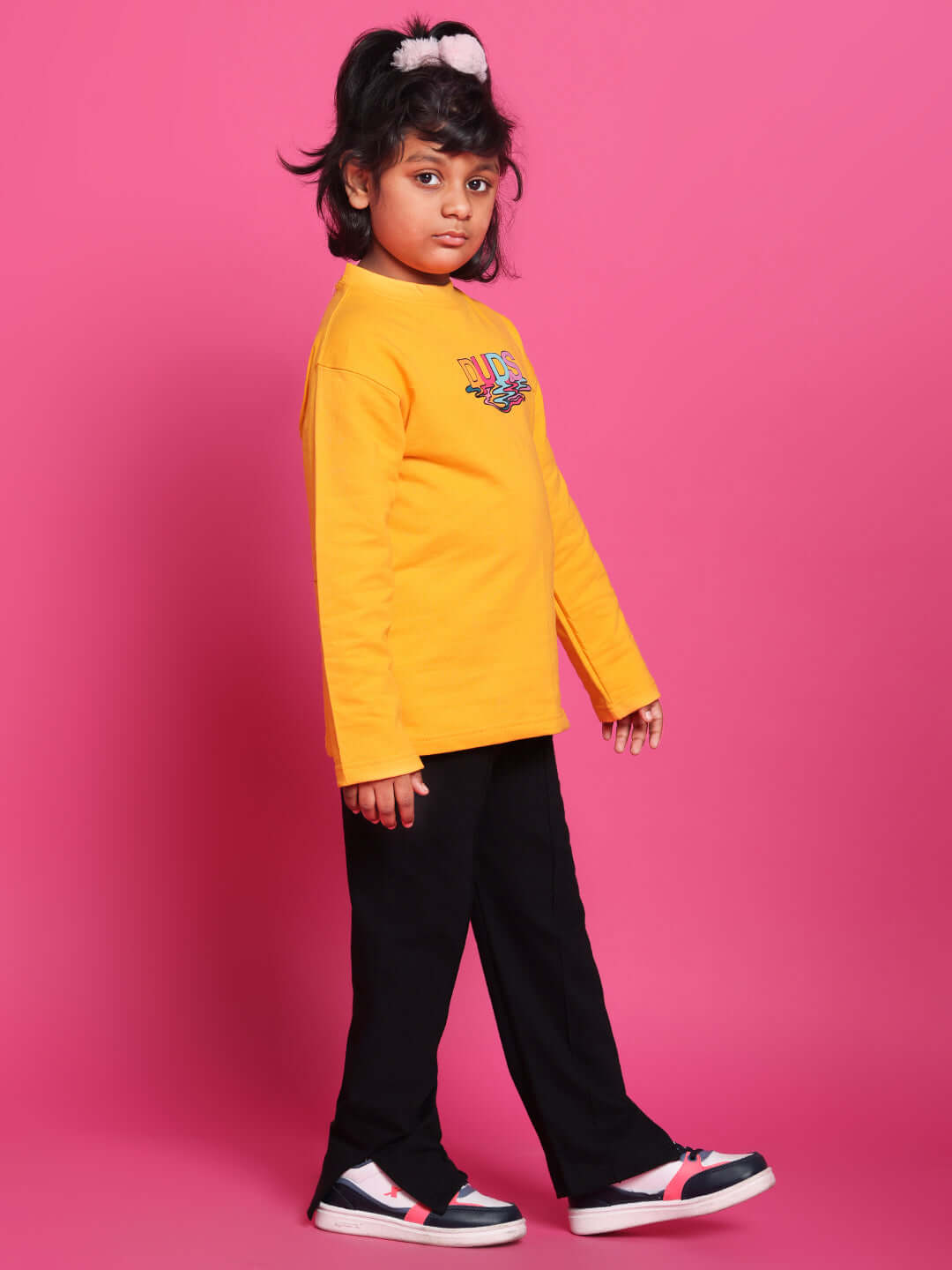 Child wearing CUBE CO-ORD in yellow-black against a pink background, showcasing DUDS fashion for boys and girls.