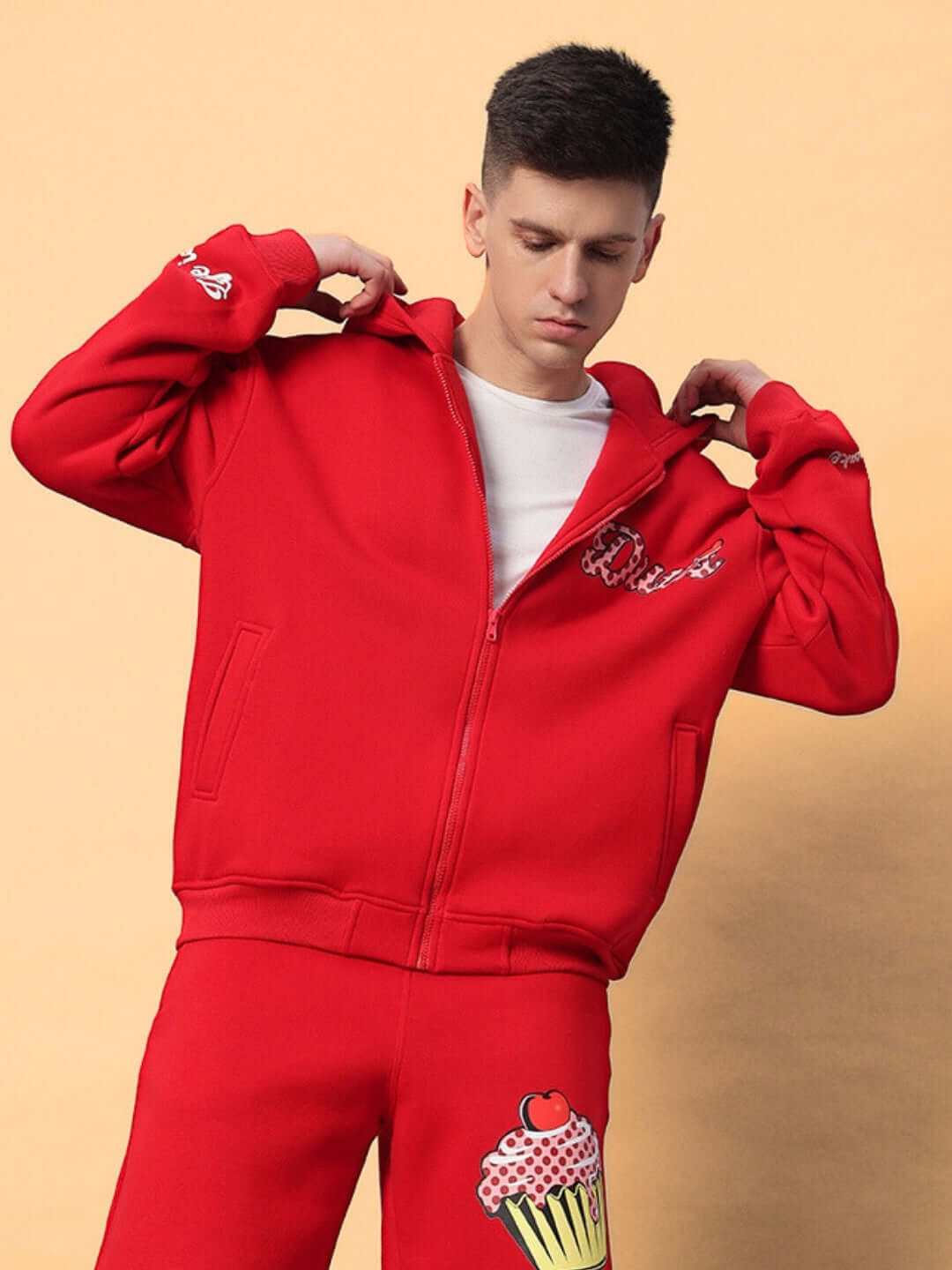 Model wears CUPCAKE COTTON FLEECE HOODIE RED in casual style, showcasing bold streetwear fashion with vivid red color against beige background.