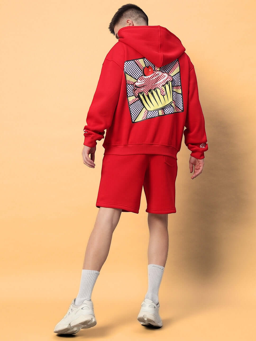 Back view of man wearing CUPCAKE COTTON FLEECE CO-ORD RED set with graphic design on hoodie, showcasing streetwear style.